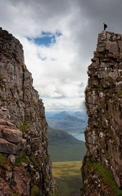 A person is standing on top of a rocky cliff.
