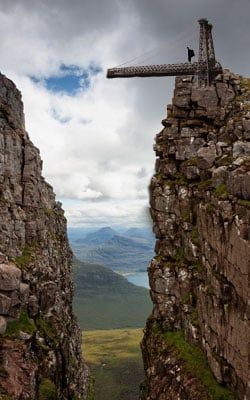A person is standing on top of a rocky cliff.