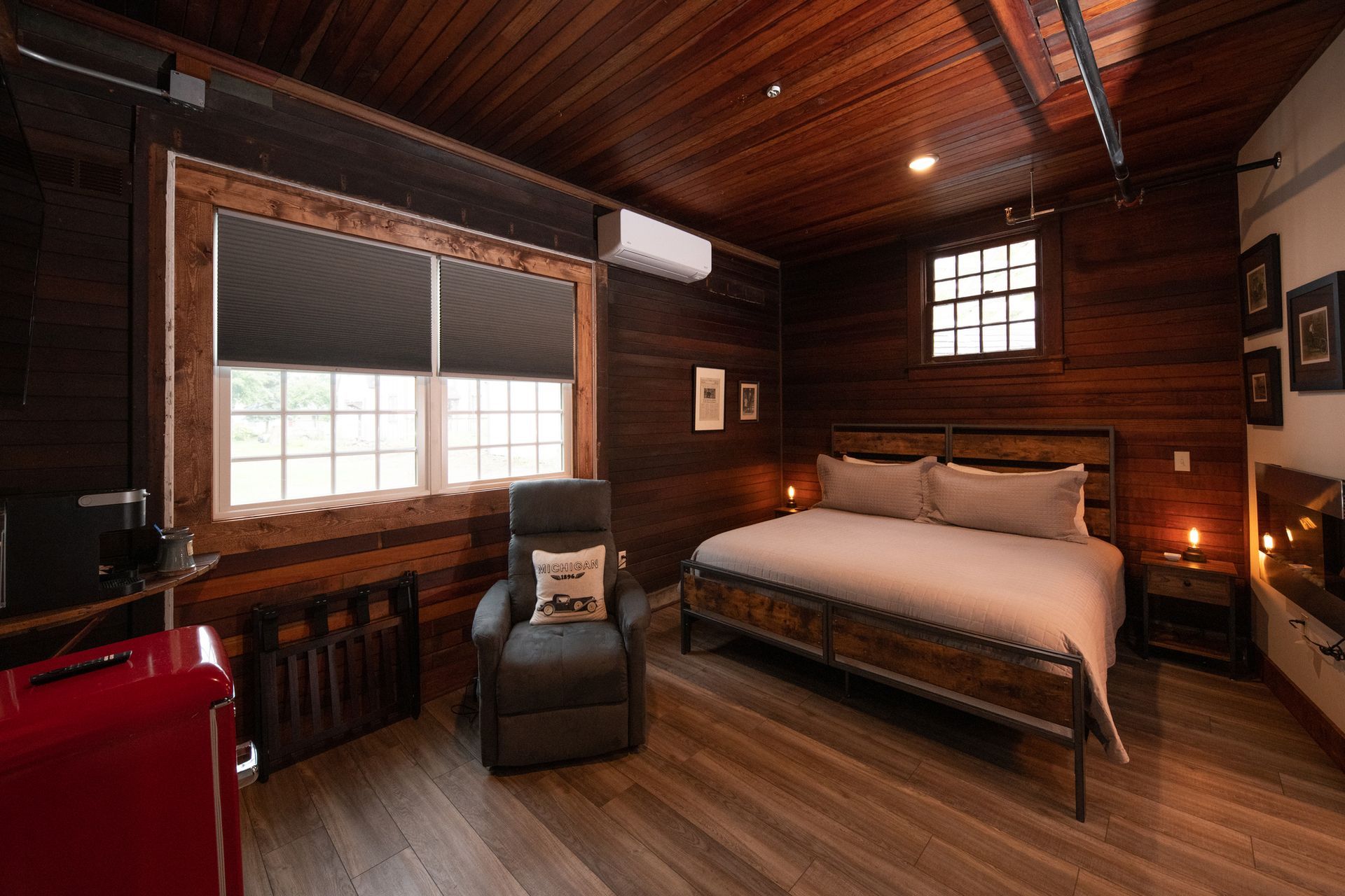 A bedroom with a bed , chair , and refrigerator.