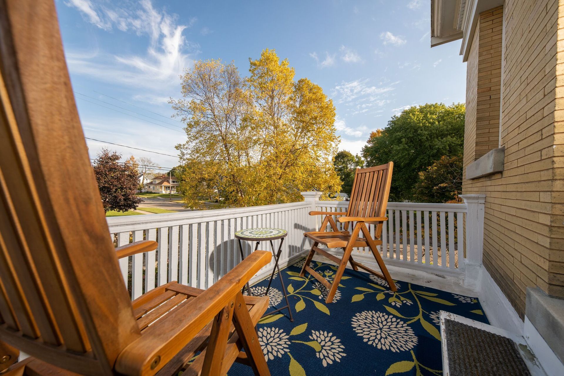 A balcony with two wooden chairs and a table
