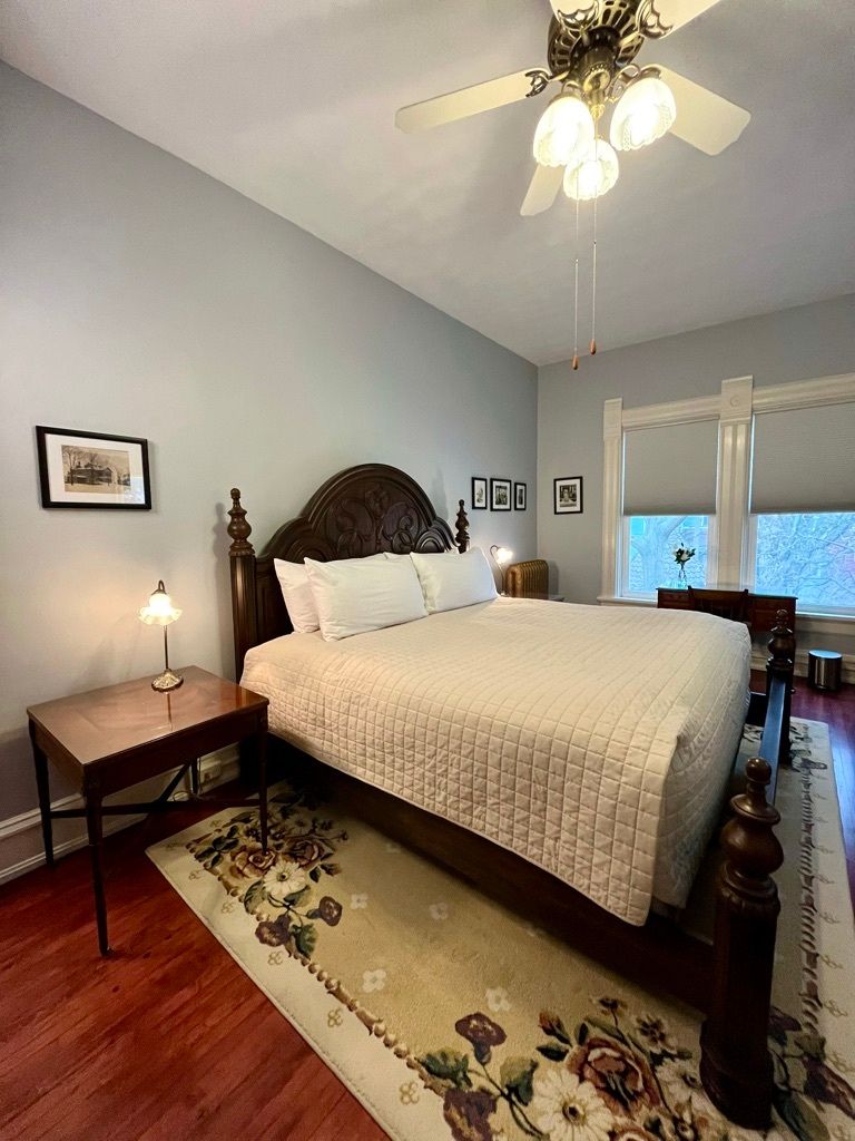 A bedroom with a king size bed and a ceiling fan.