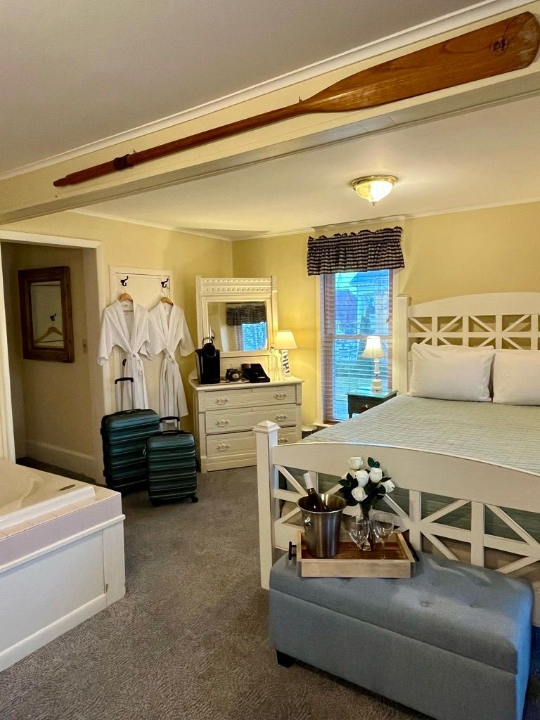 A bedroom with a bed , dresser , mirror and jacuzzi.