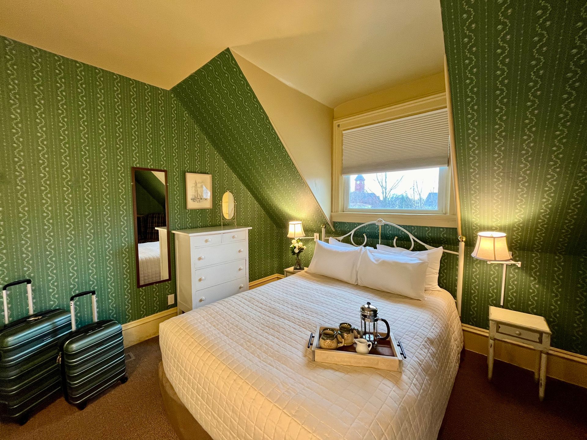 A hotel room with a king size bed and two suitcases