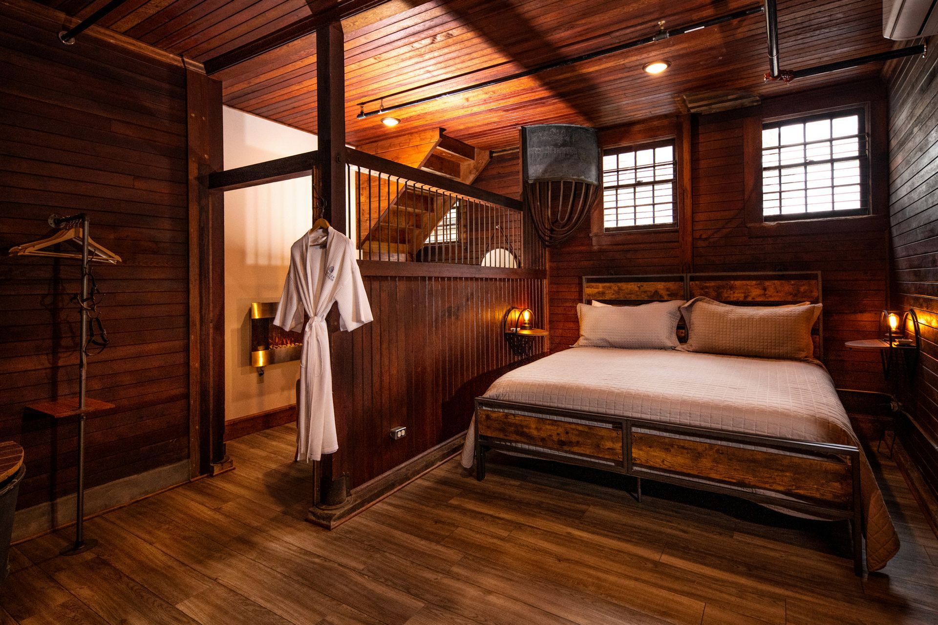 A bedroom in a wooden house with a bed and a bathrobe hanging on the wall.