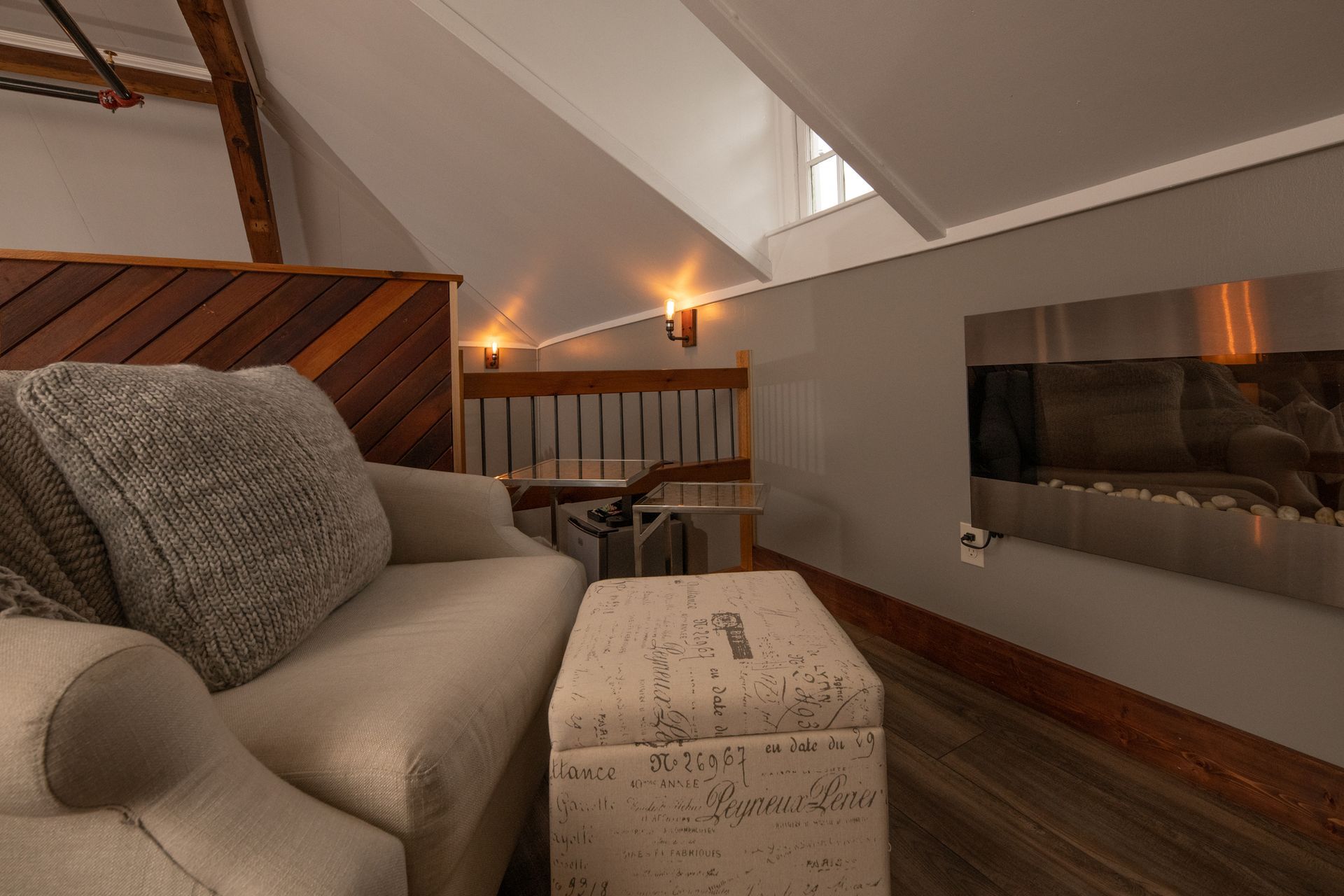 A living room with a chair and ottoman and a fireplace.