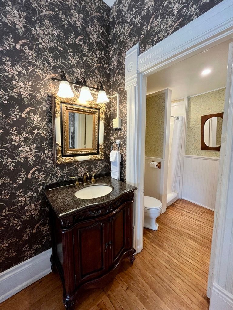 A bathroom with a sink , mirror , toilet and shower.