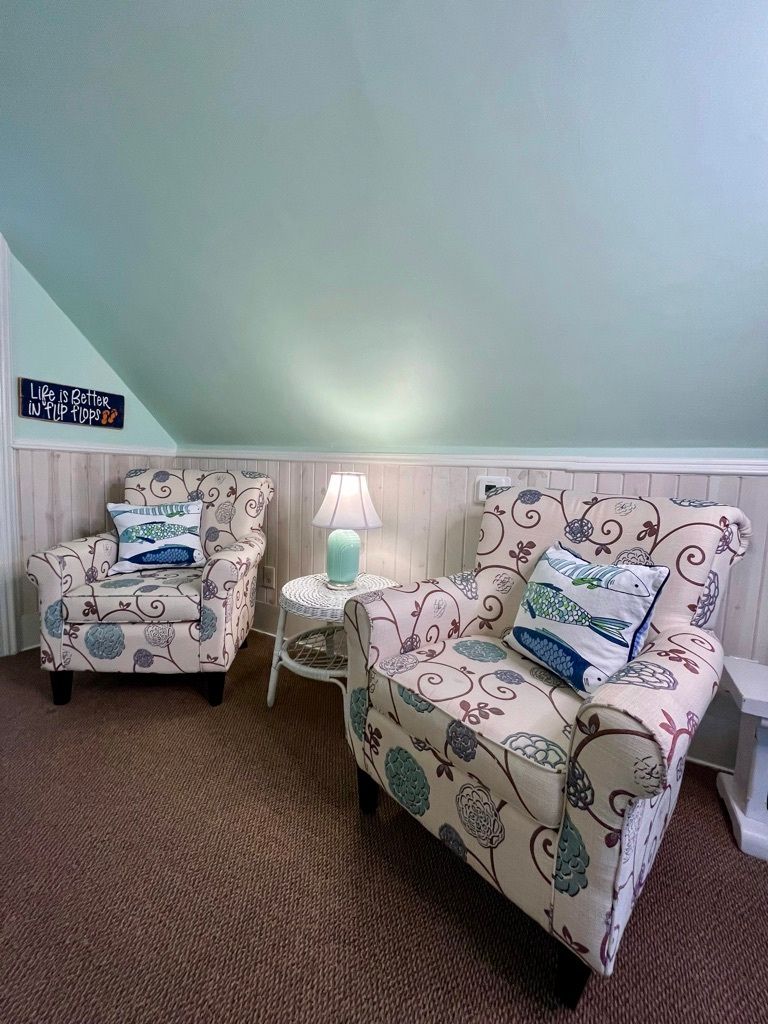 A living room with two chairs , a table and a lamp.