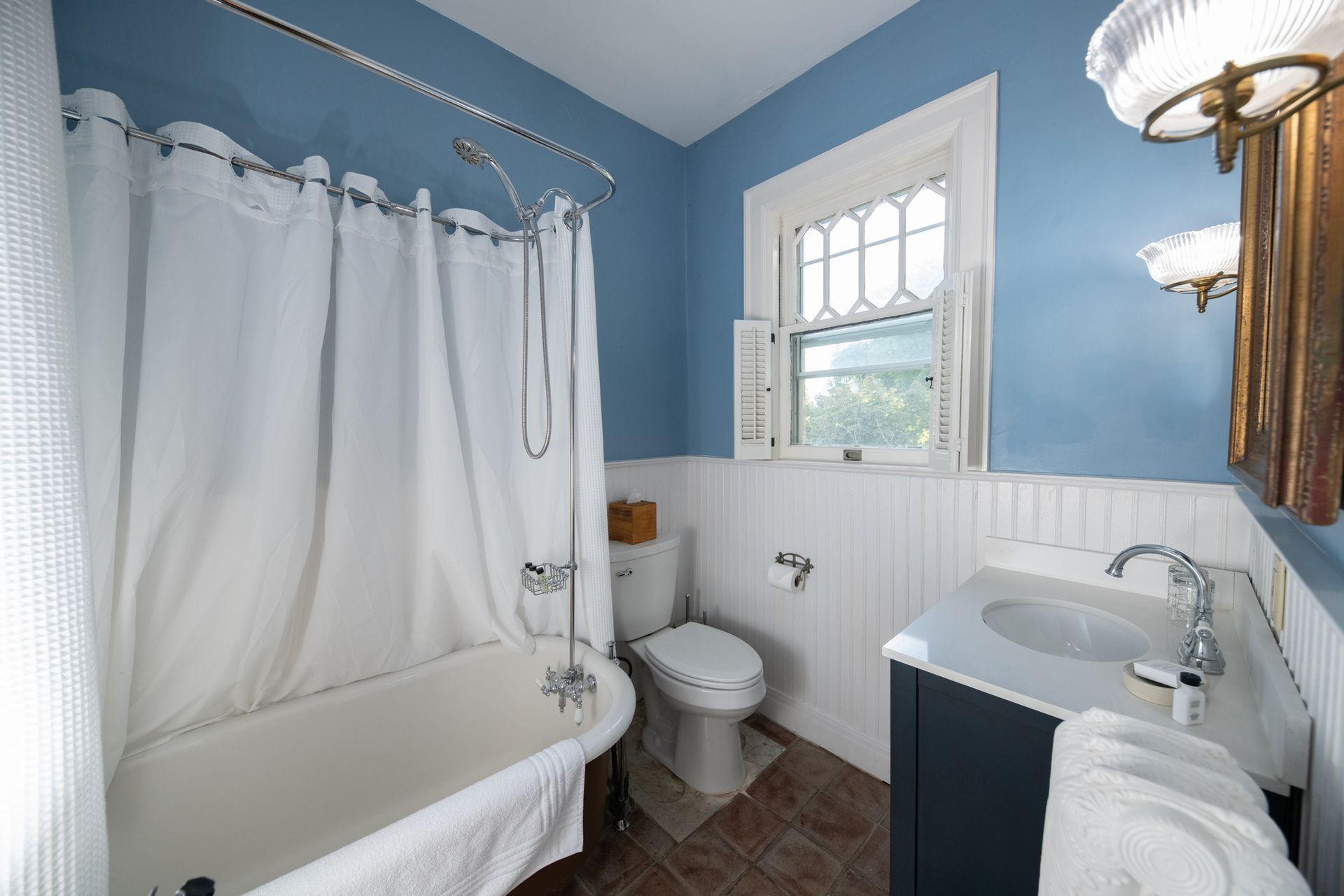 A bathroom with a tub , toilet , sink and window.