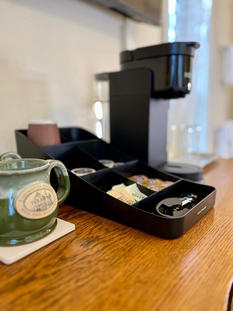 A coffee maker is sitting on a wooden counter next to a cup.