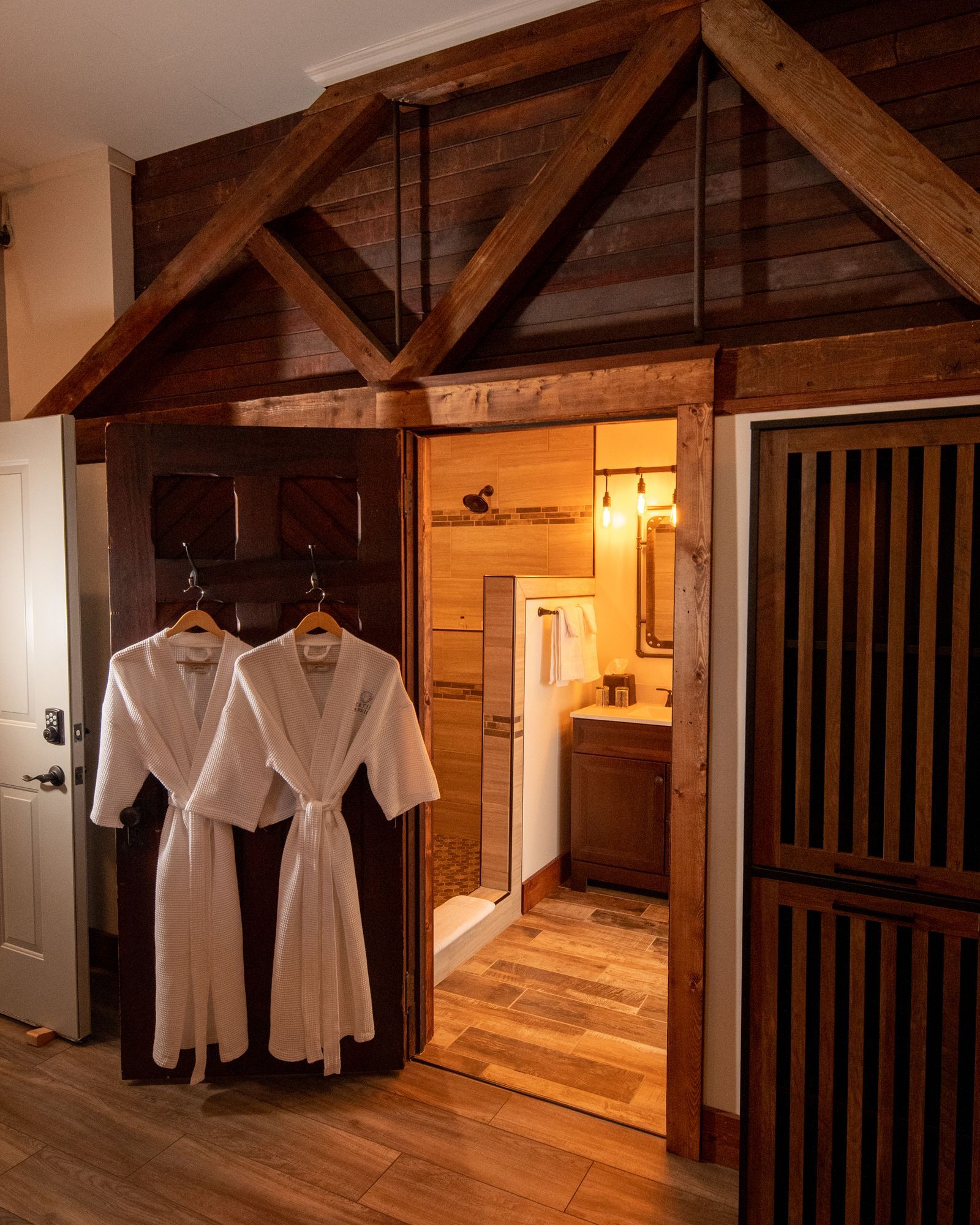 Two bathrobes are hanging on a door in a bathroom.