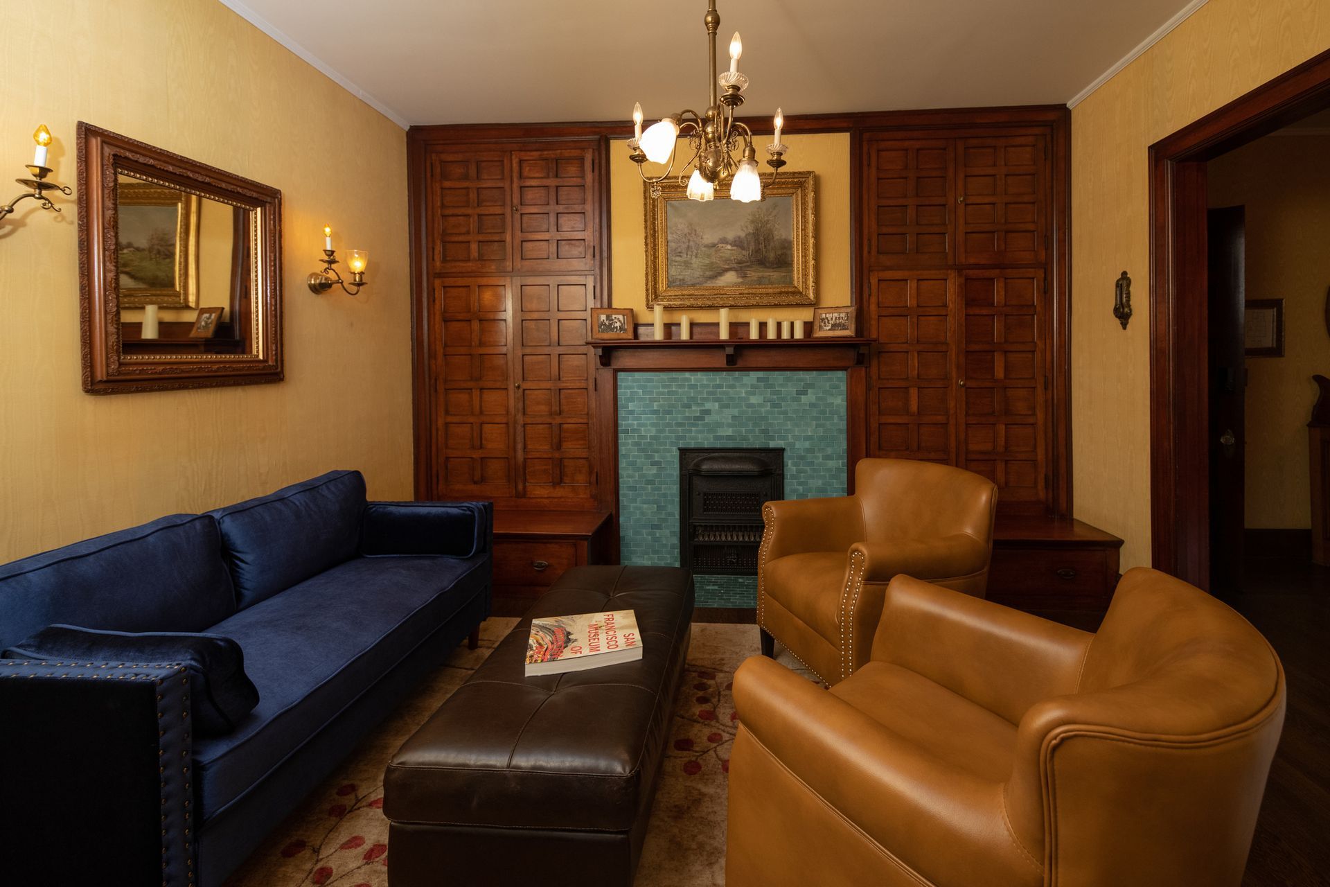 A living room with a blue couch and two brown chairs