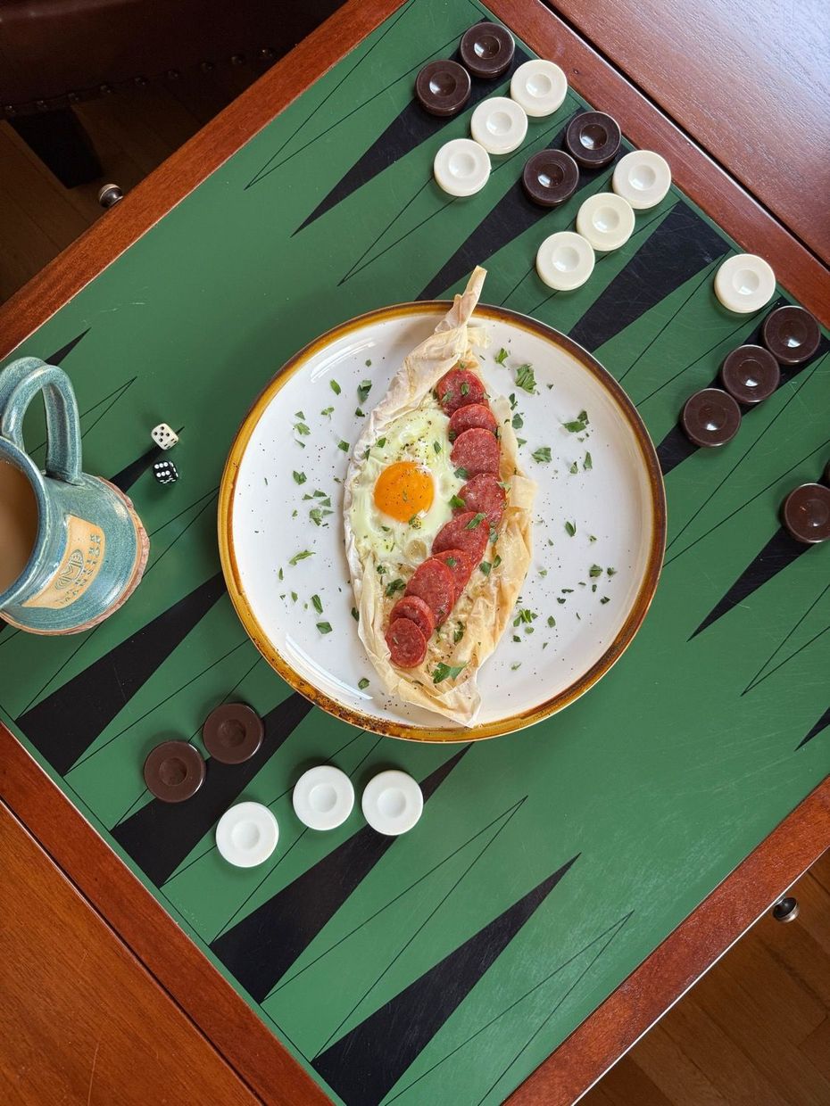 A plate of food is sitting on top of a backgammon board.