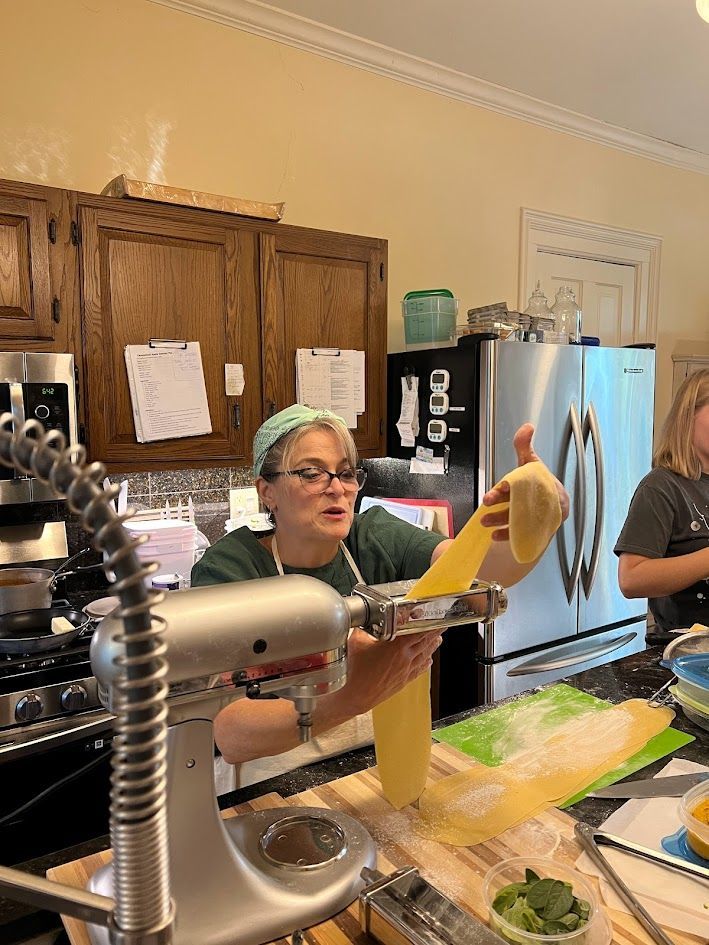 A woman is holding a piece of pasta in a kitchen.
