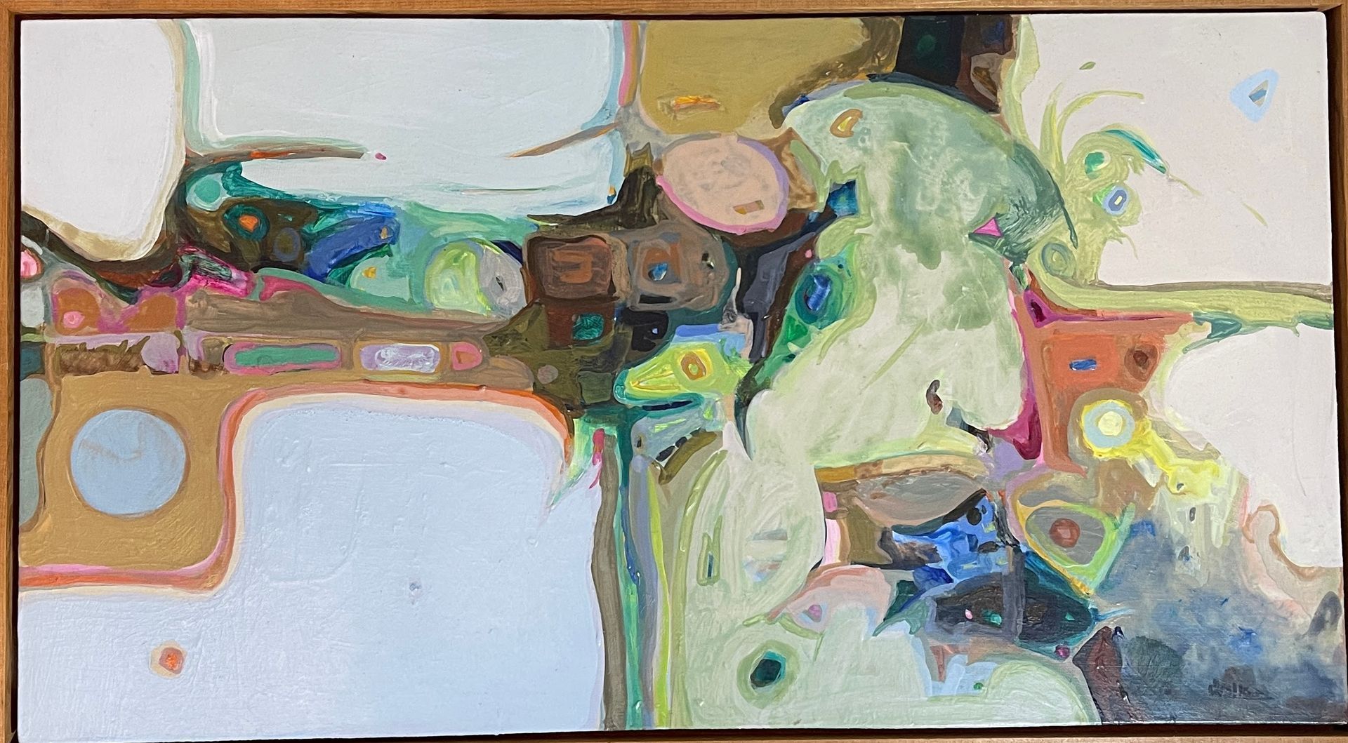 A colorful painting is hanging on a wall in a wooden frame.