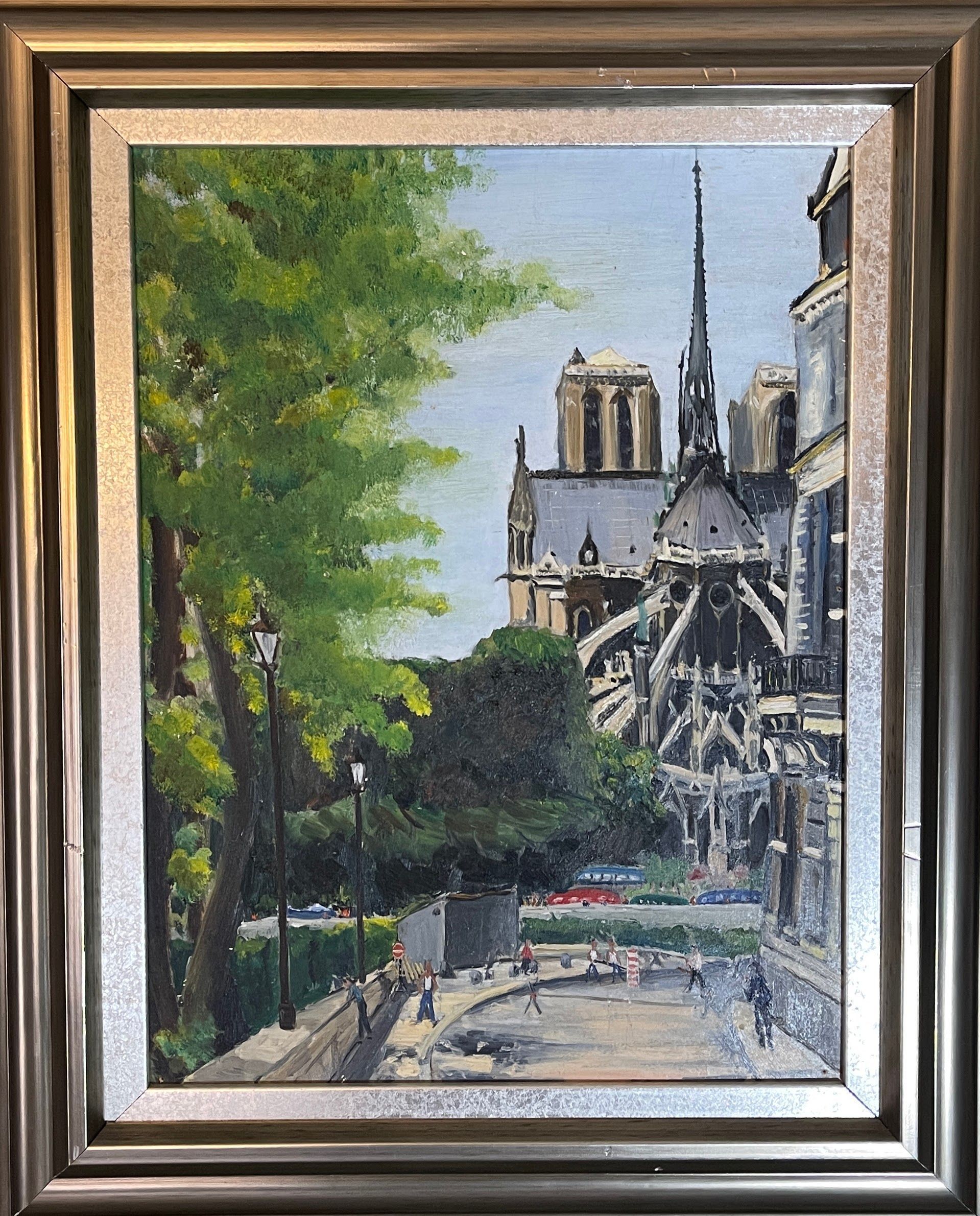 A painting of notre dame cathedral in paris is in a silver frame.