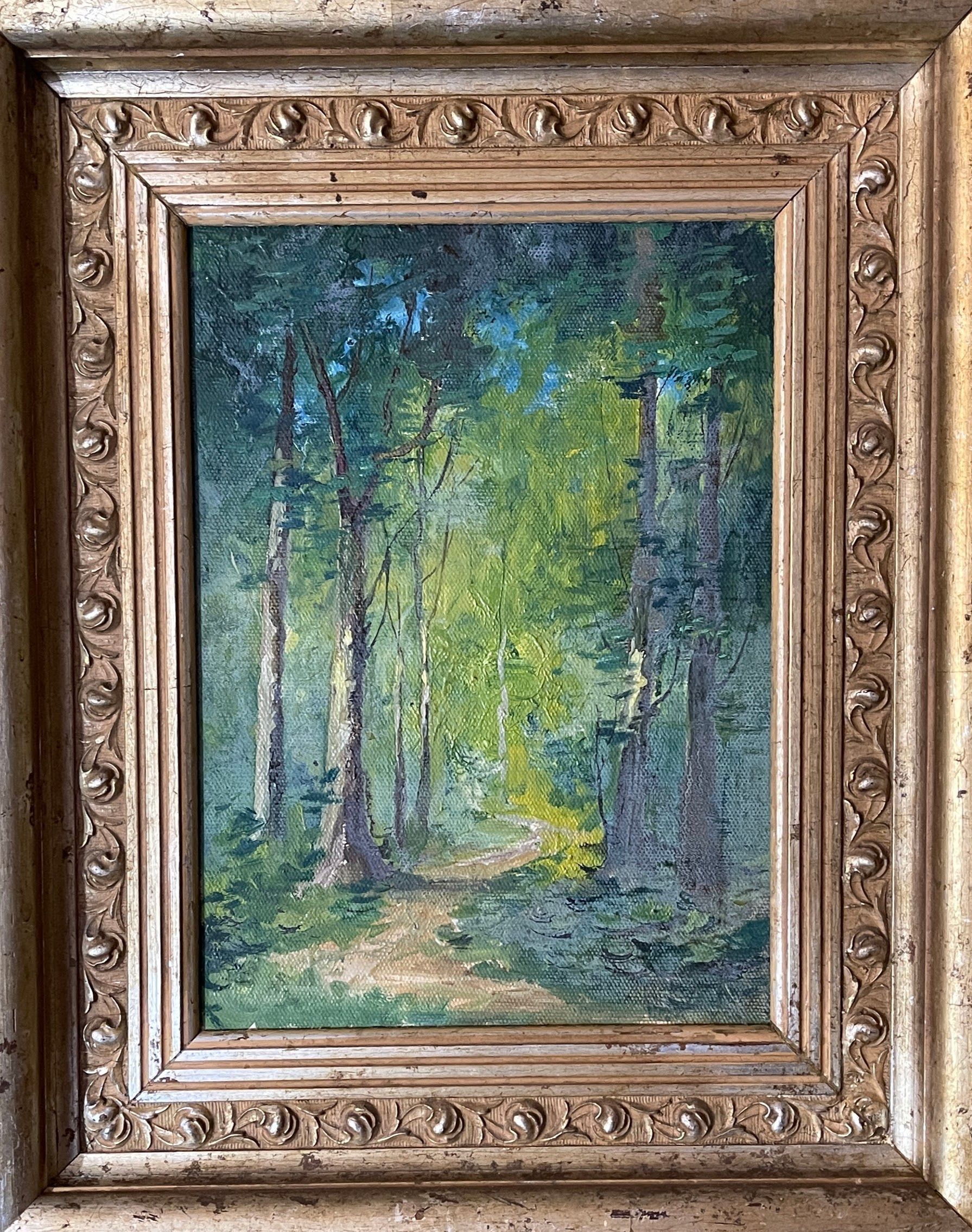 A painting of a path through a forest in a gold frame.