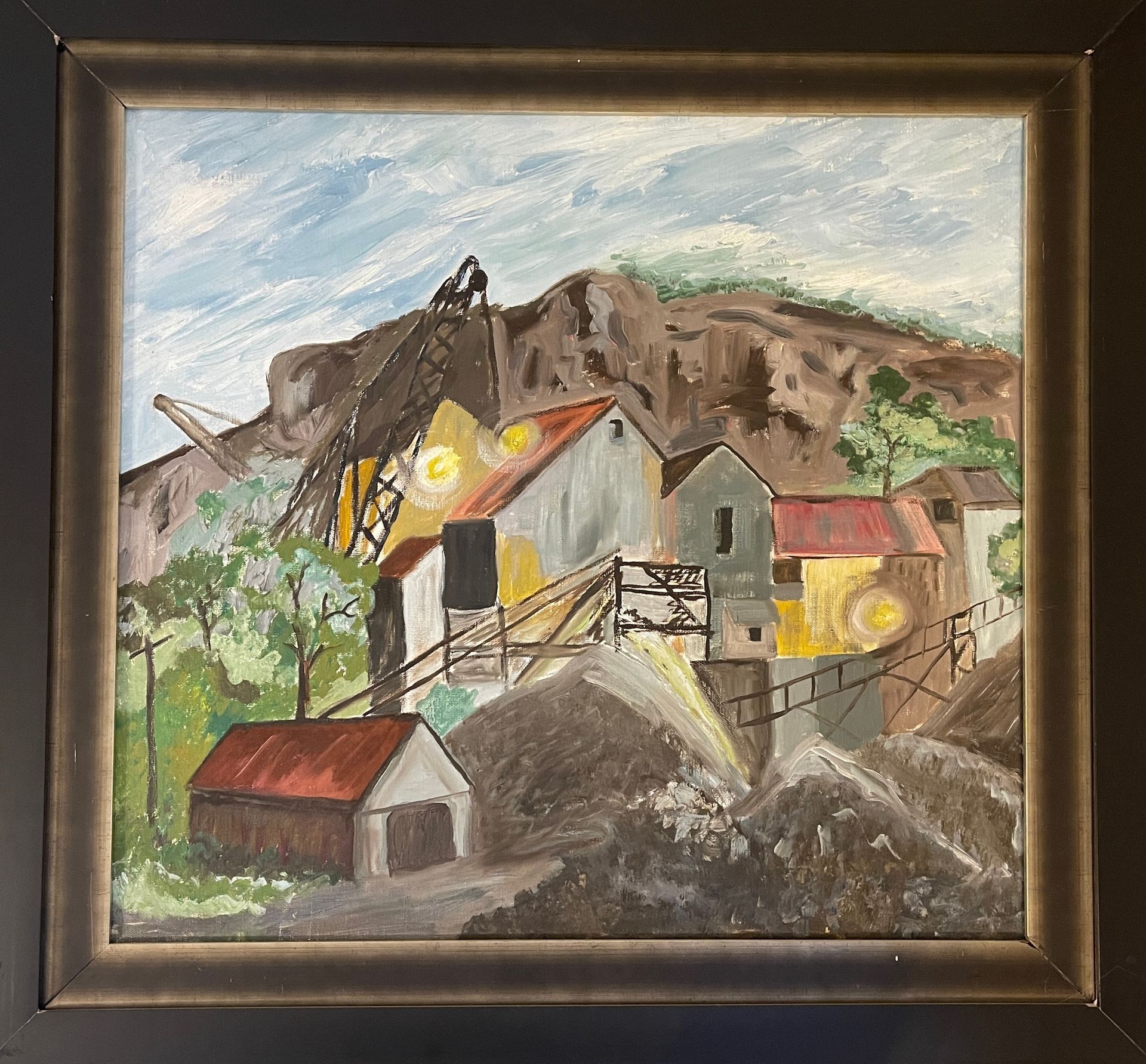 A framed painting of a landscape with houses and a crane