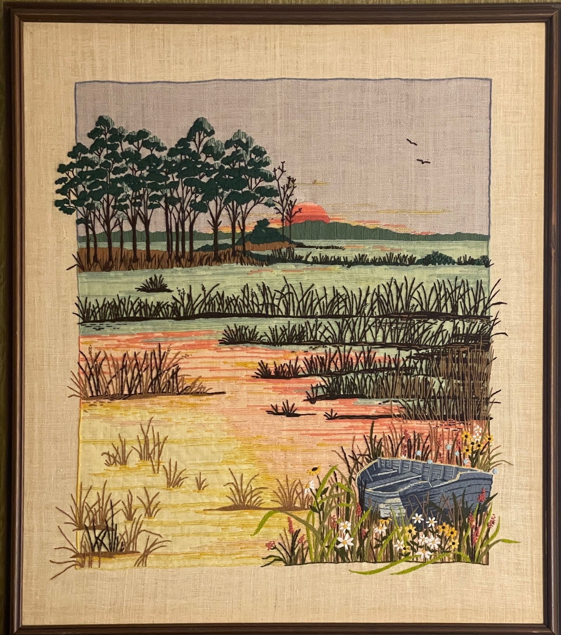 A cross stitch painting of a swamp with trees in the background.