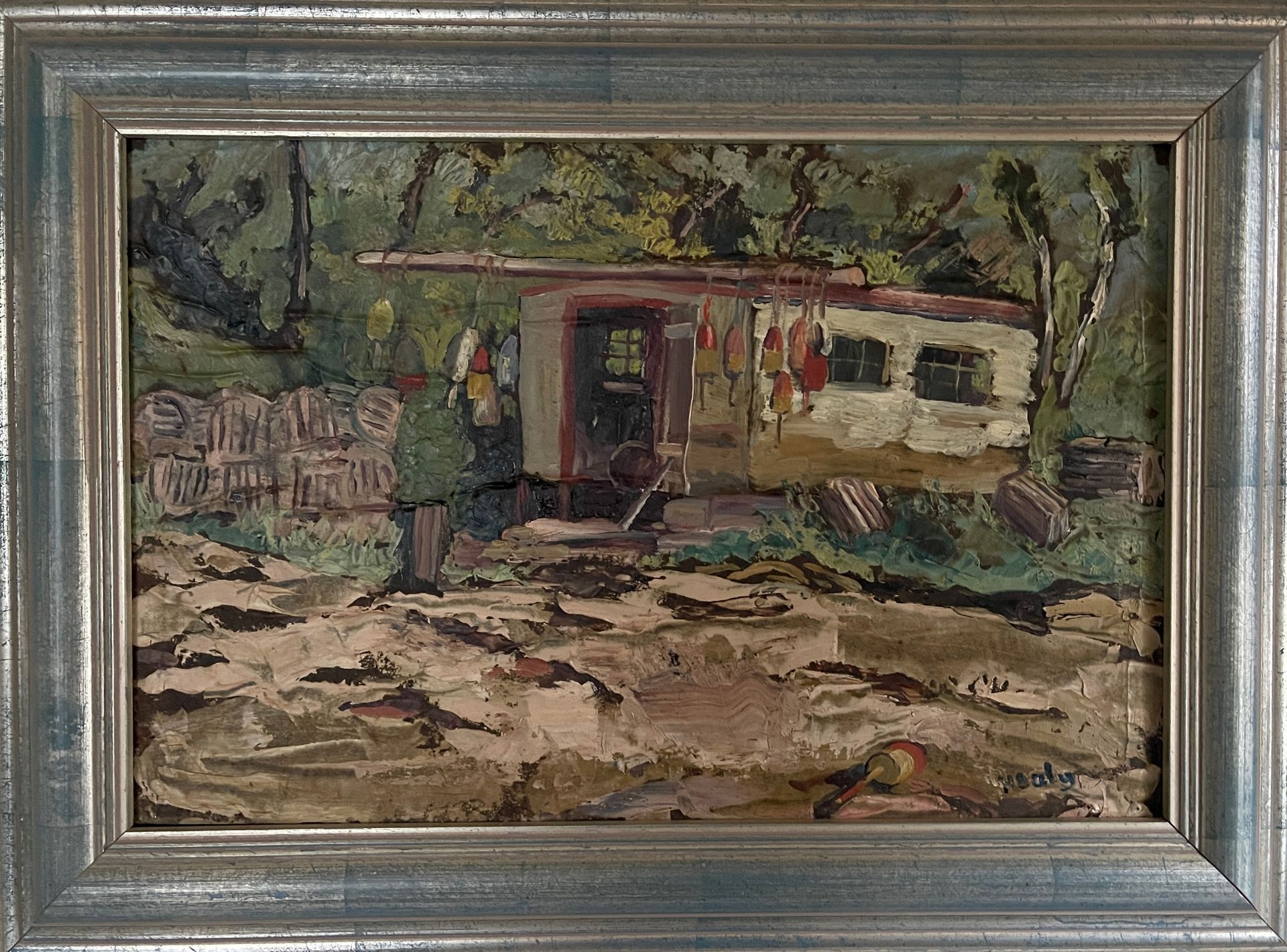 A framed painting of a house in the woods