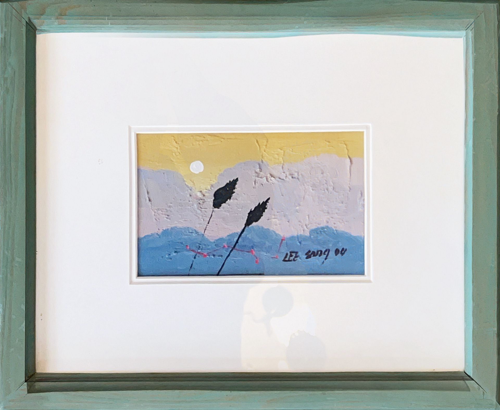 A framed painting of a landscape with a blue frame