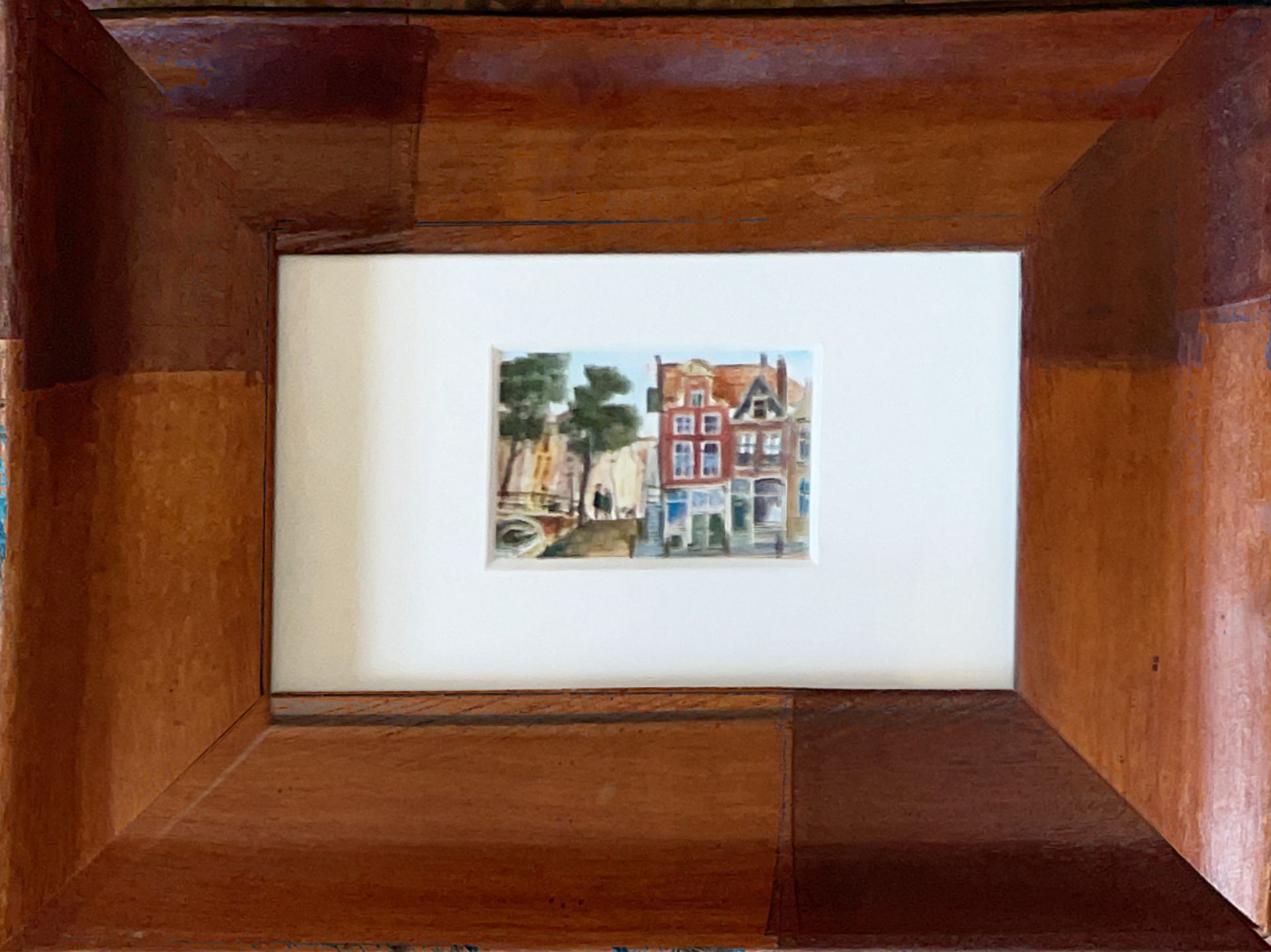 A picture of a house in a wooden frame on a table.