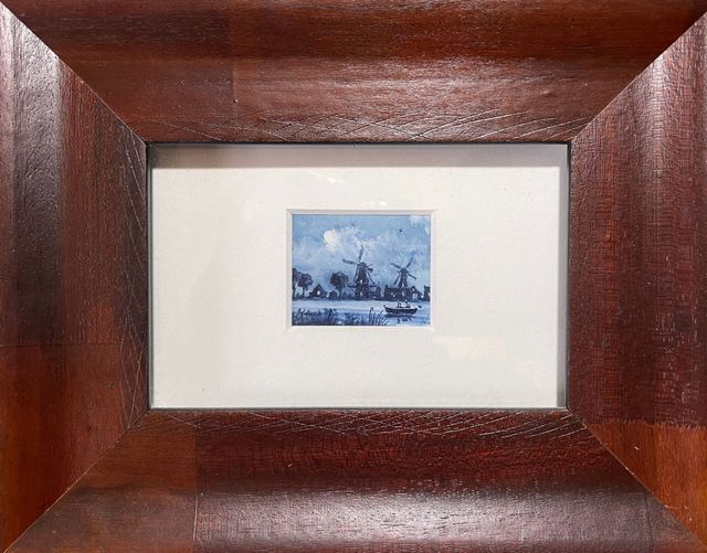A picture of a windmill in a wooden frame.