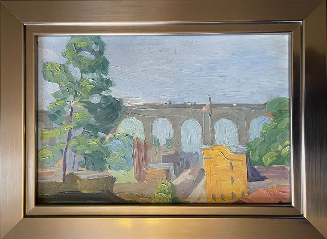 A painting of a bridge in a frame on a wall.