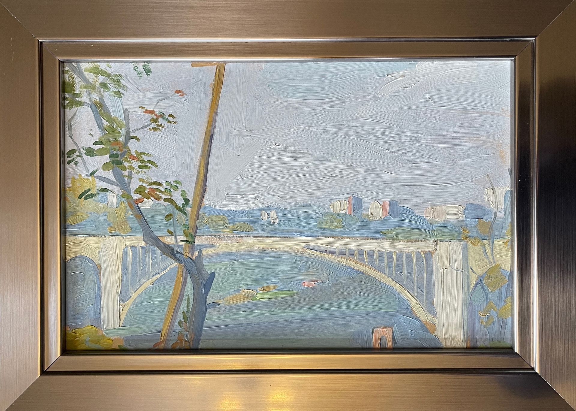 A painting of a bridge over a river in a frame.