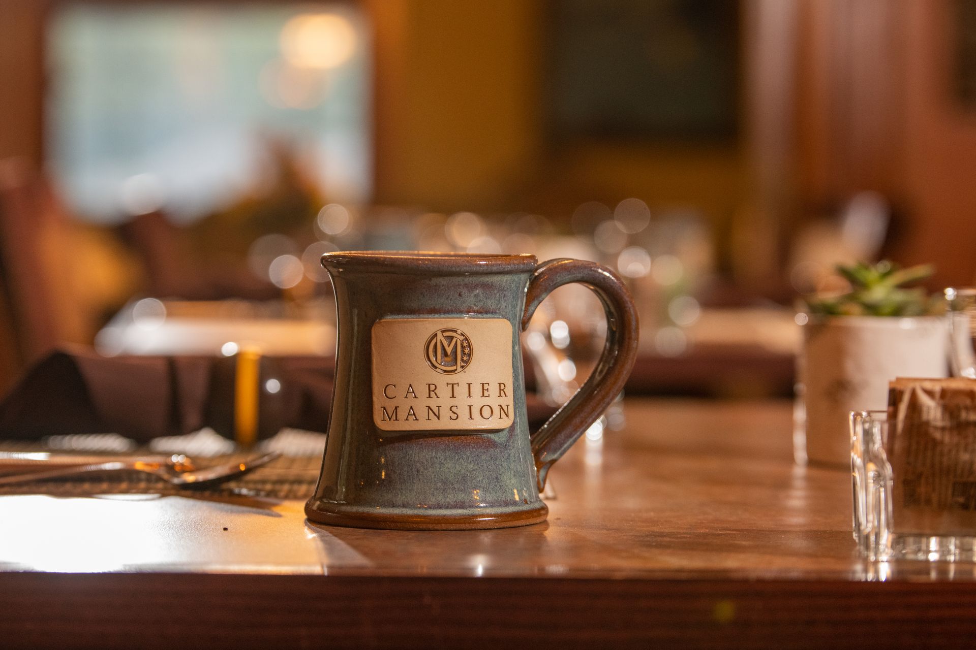 A mug is sitting on a wooden table in a restaurant.