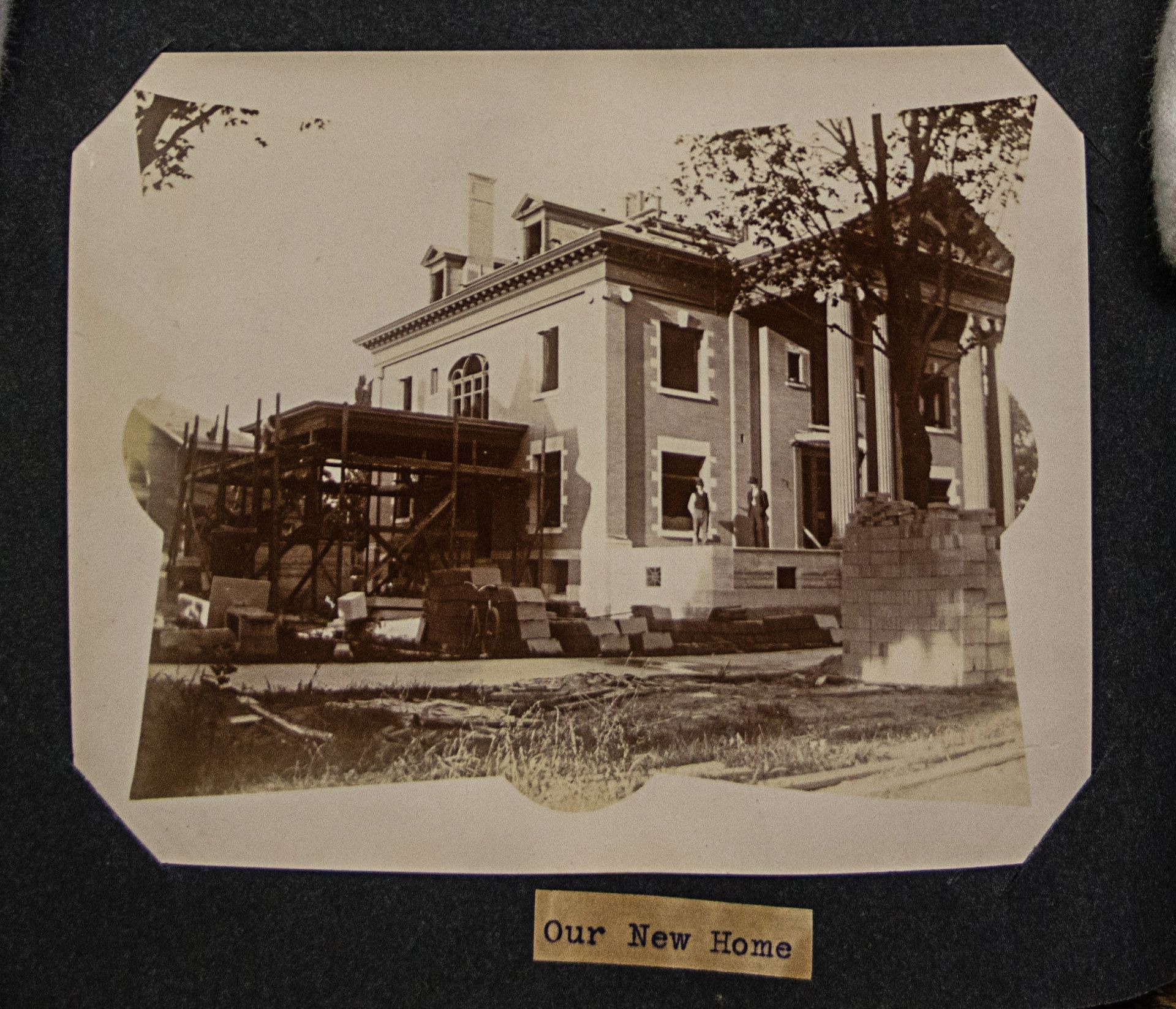 A black and white photo of a building under construction with a label that says our new home