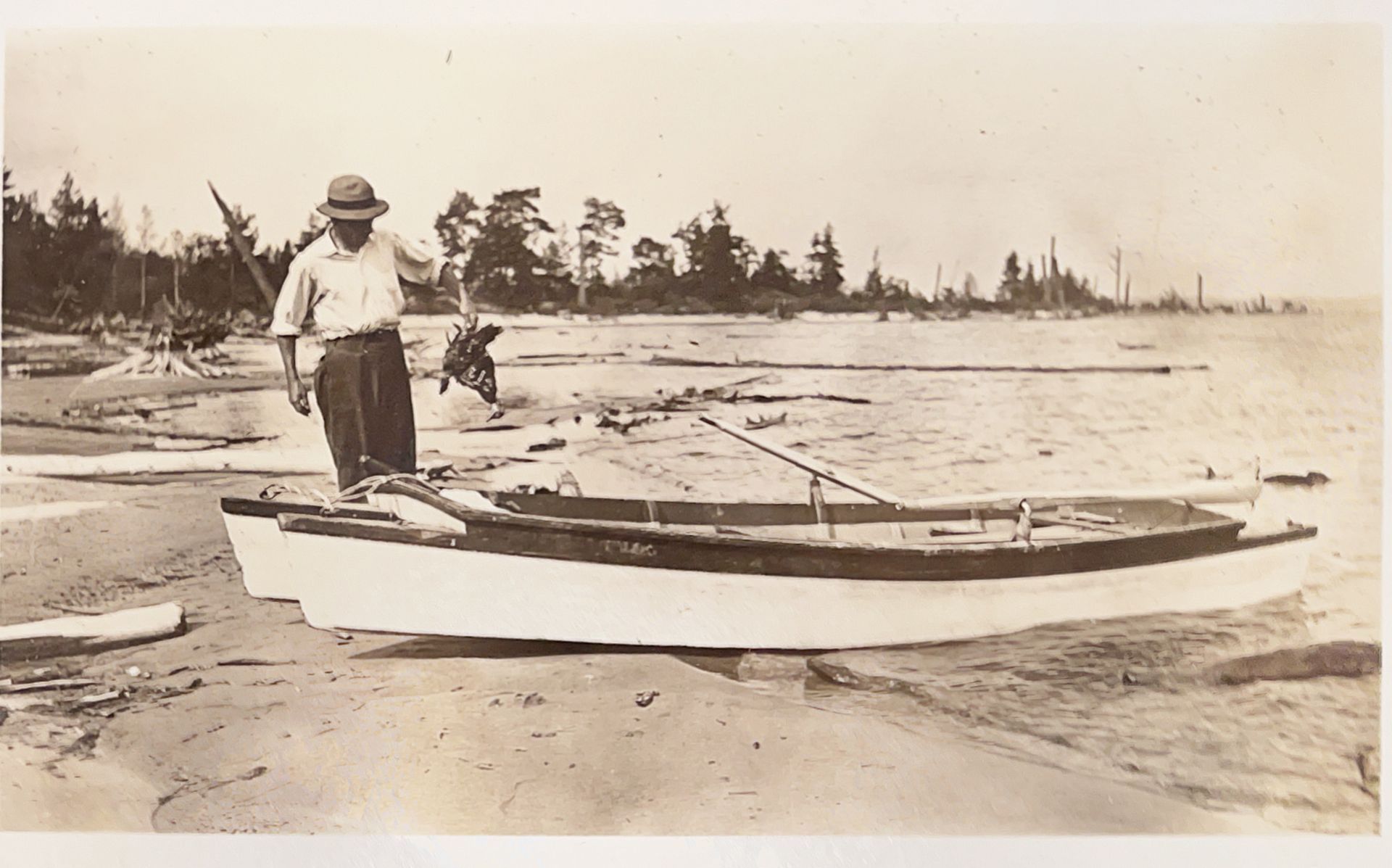 A black and white photo of a man standing next to a boat