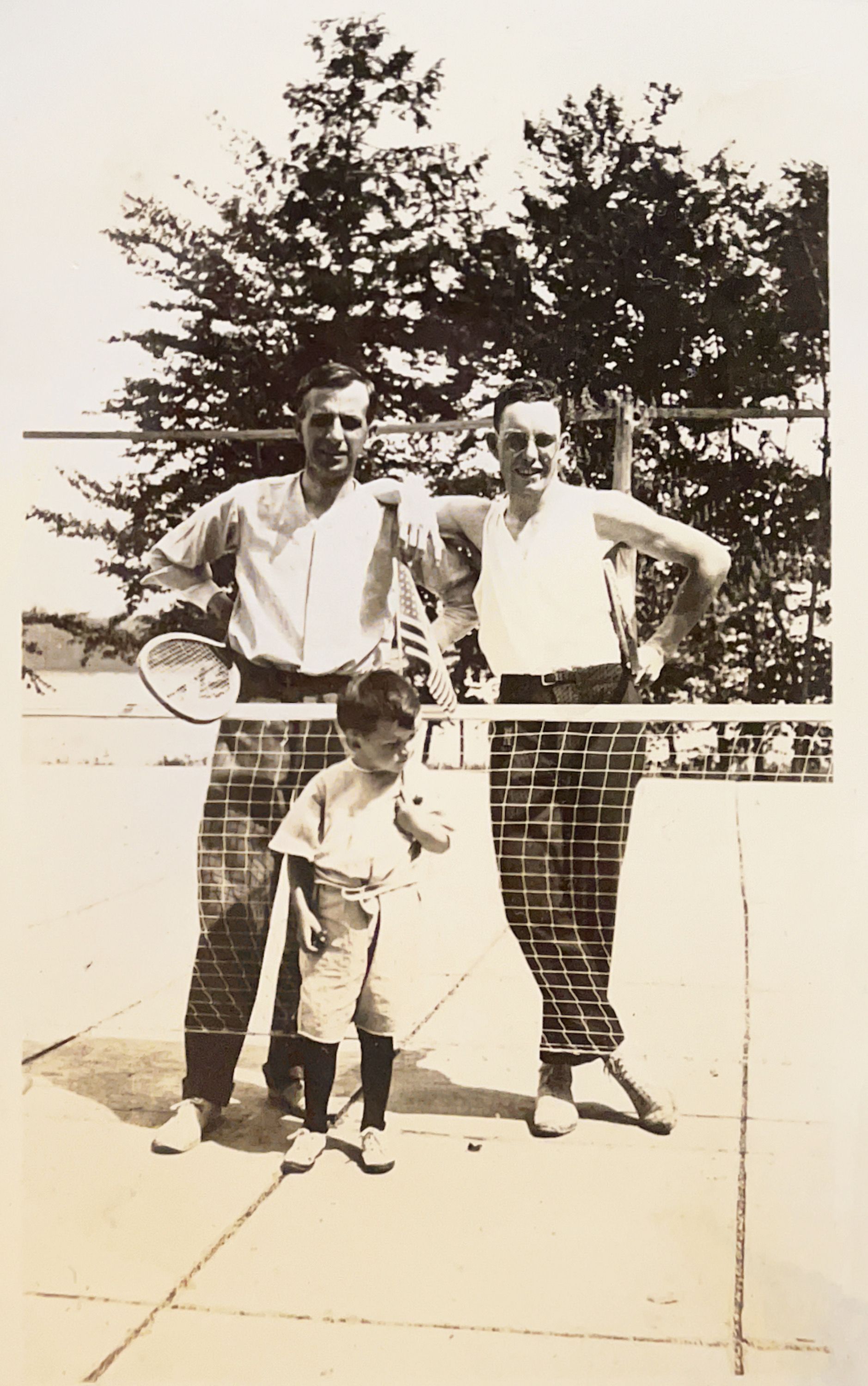 A black and white photo of three men playing tennis