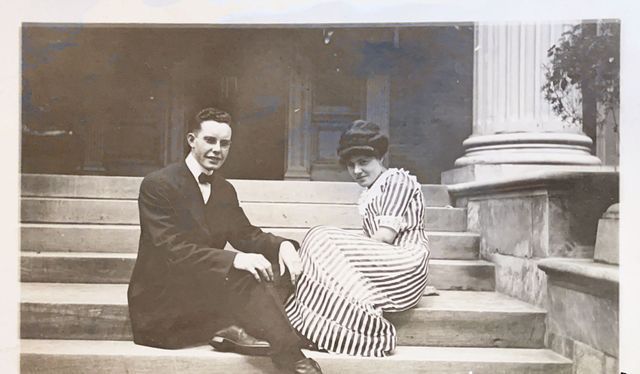 A man and a woman are sitting on the steps of a building.