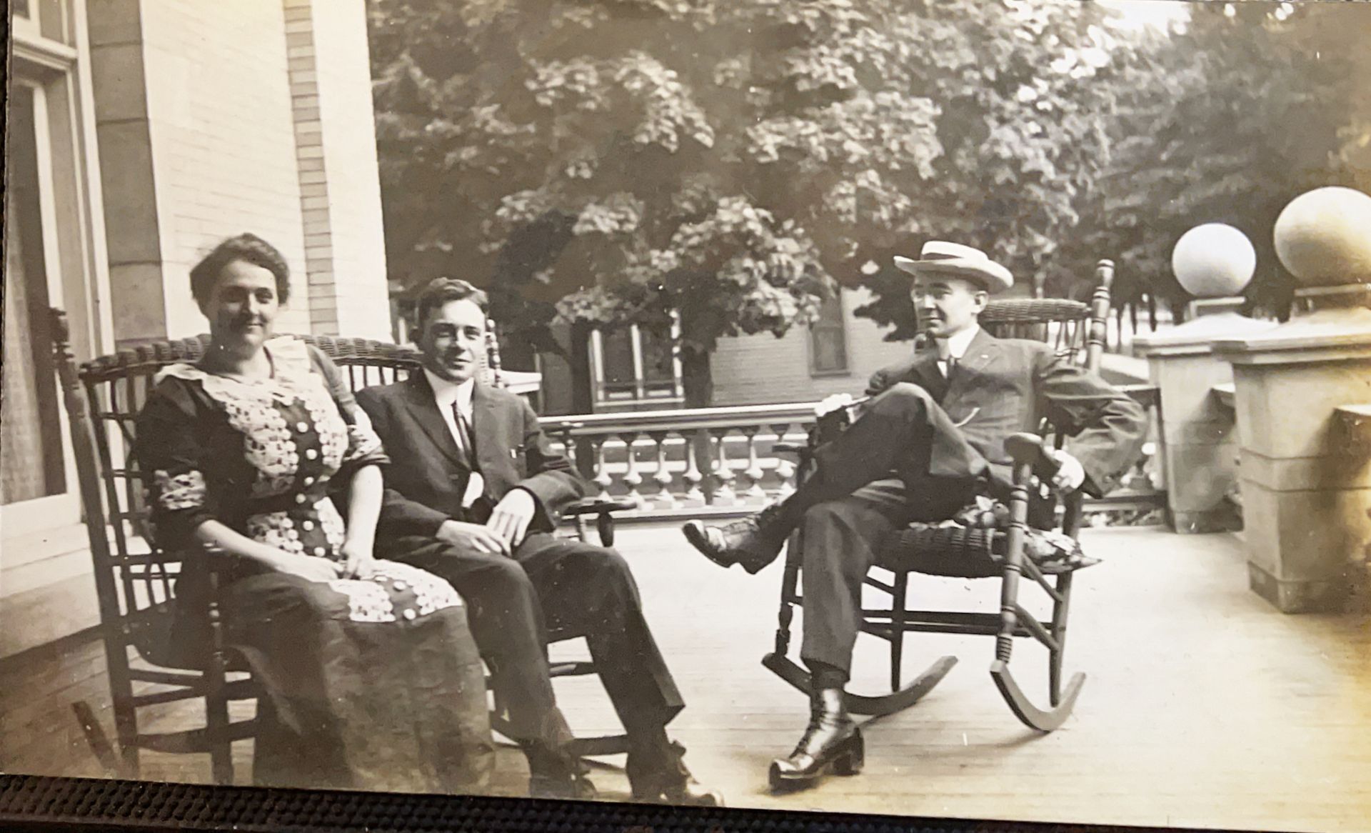A group of people are sitting in rocking chairs on a porch.