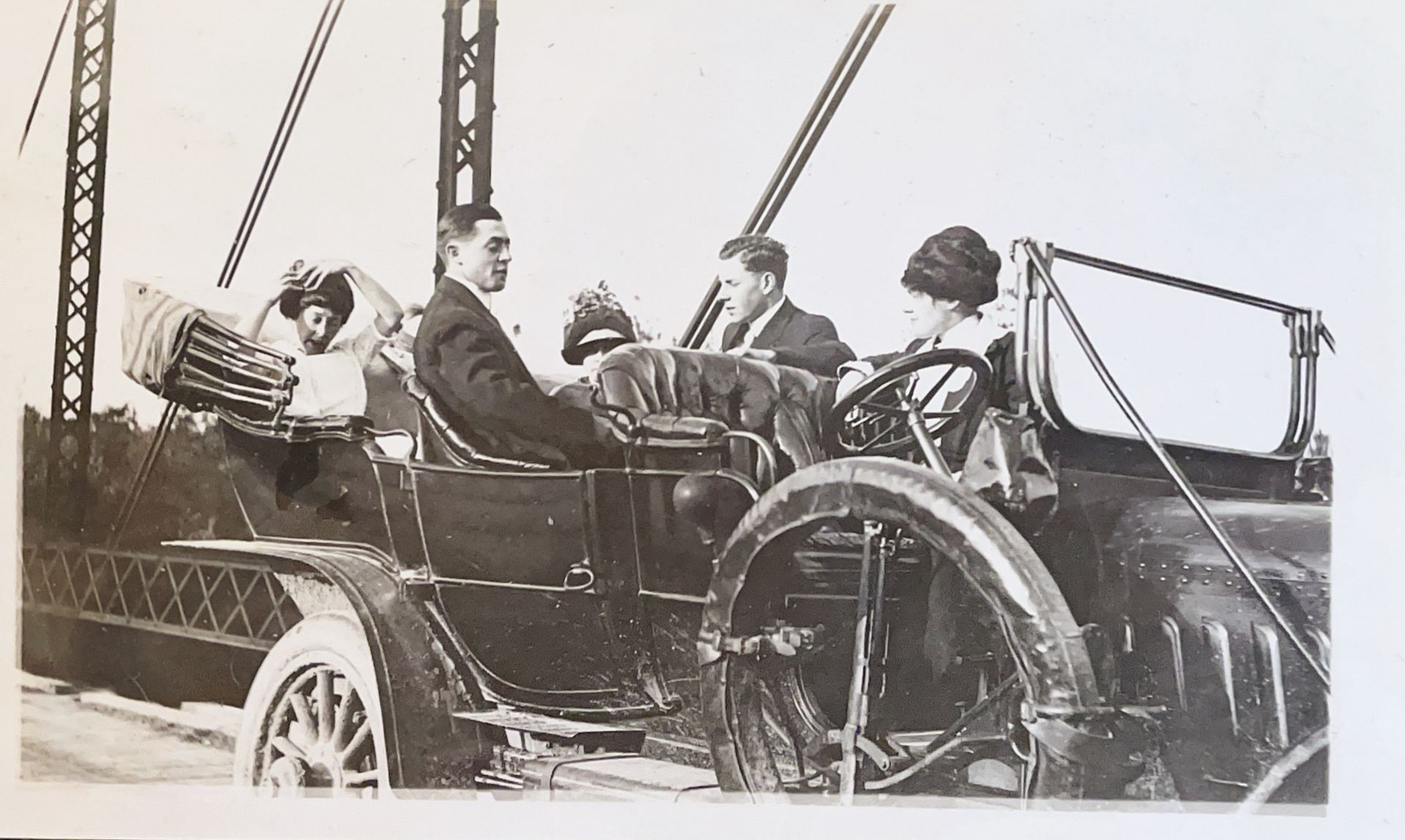 A black and white photo of a group of people in an old car