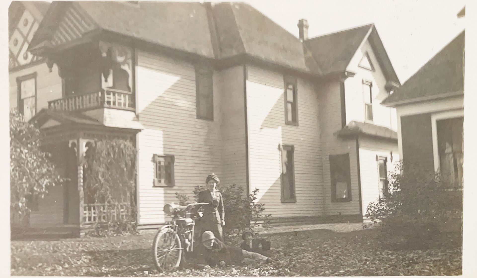 A black and white photo of a house with a motorcycle parked in front of it