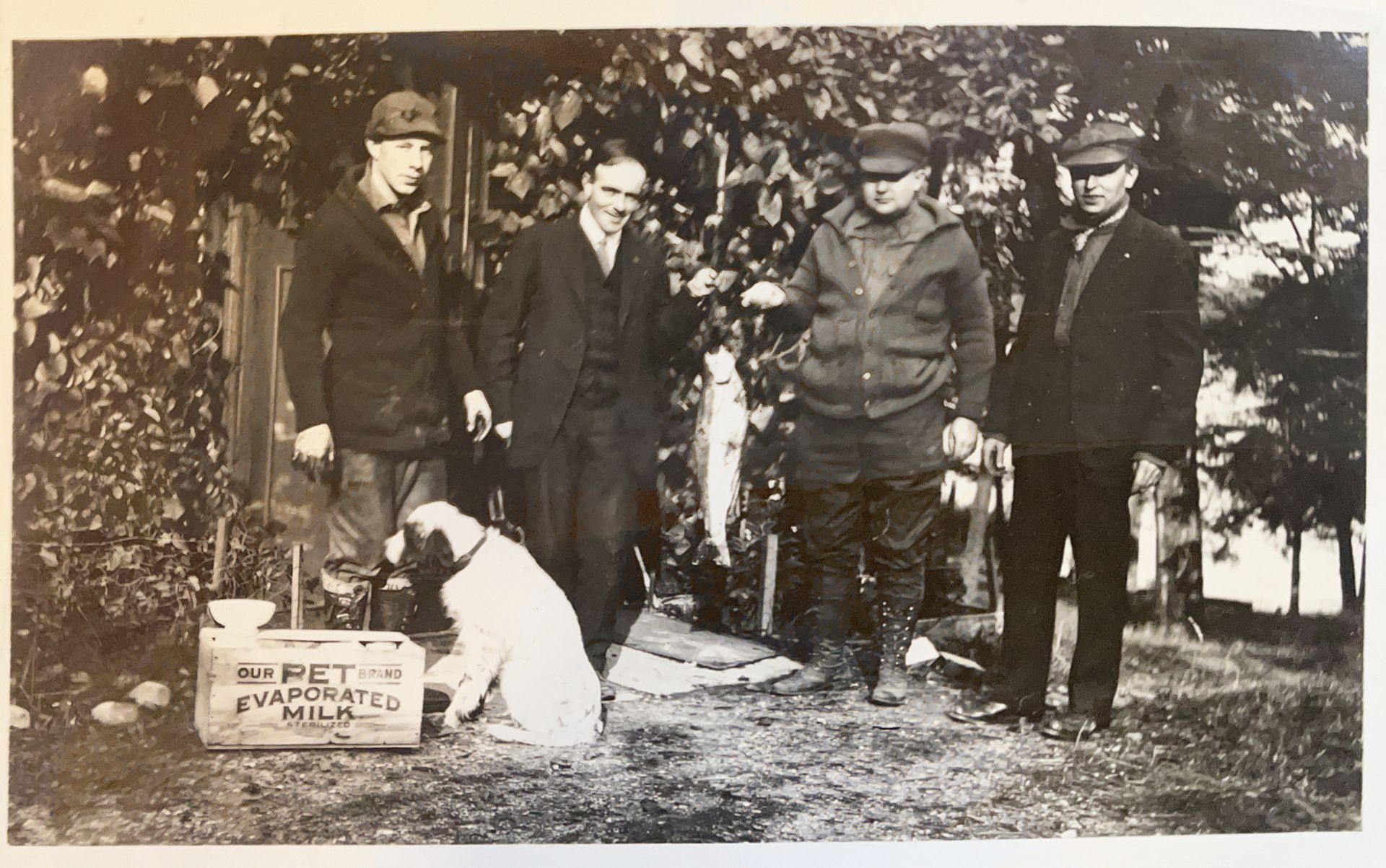 A black and white photo of a group of men and a dog