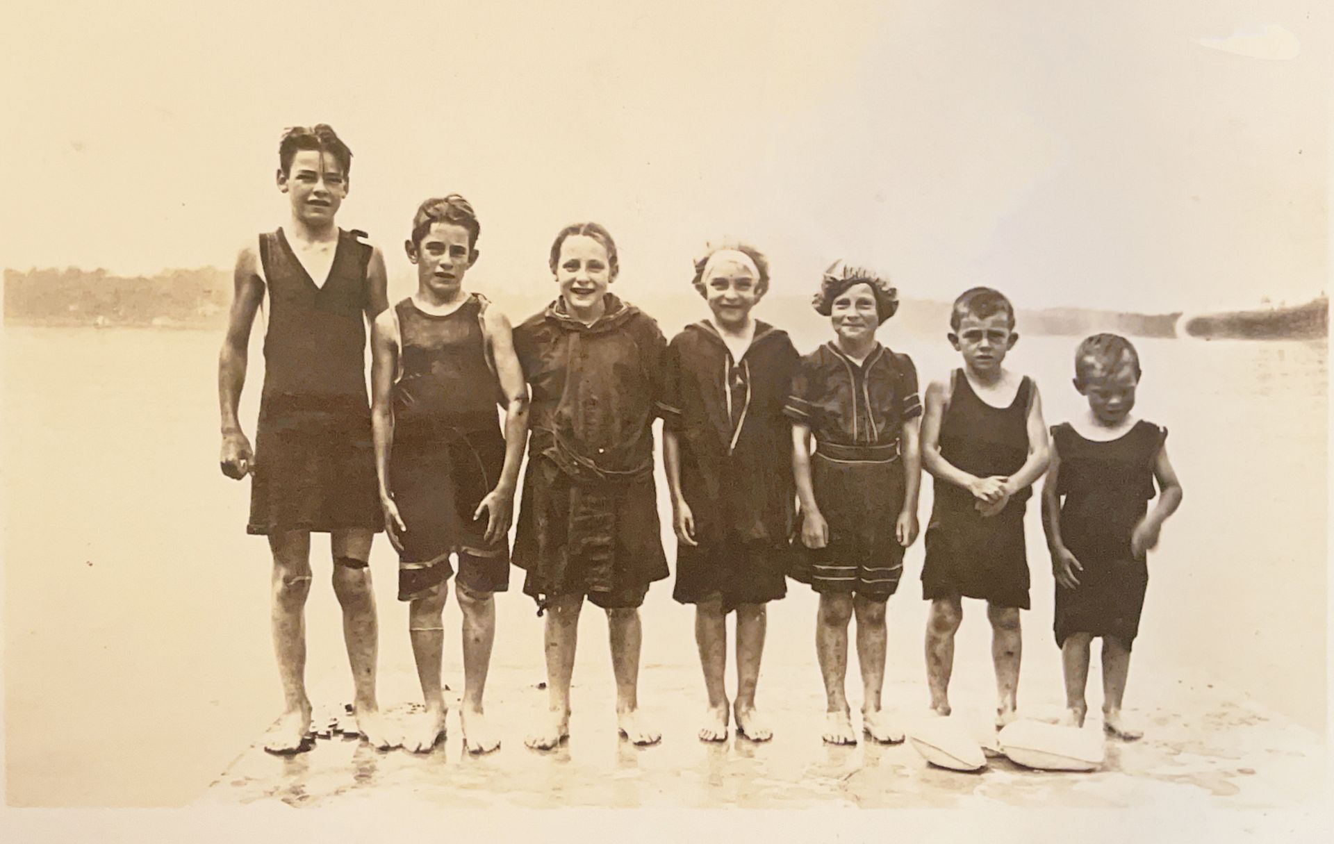 A group of children are posing for a picture on the beach
