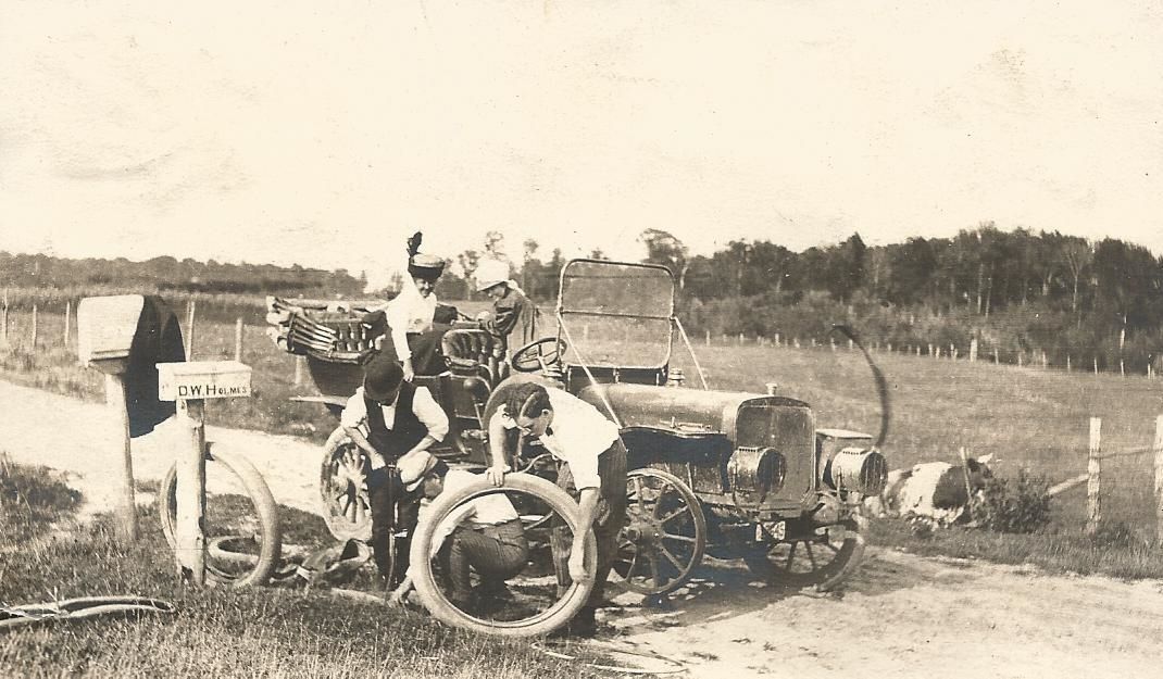 A black and white photo of a man standing next to a tractor.