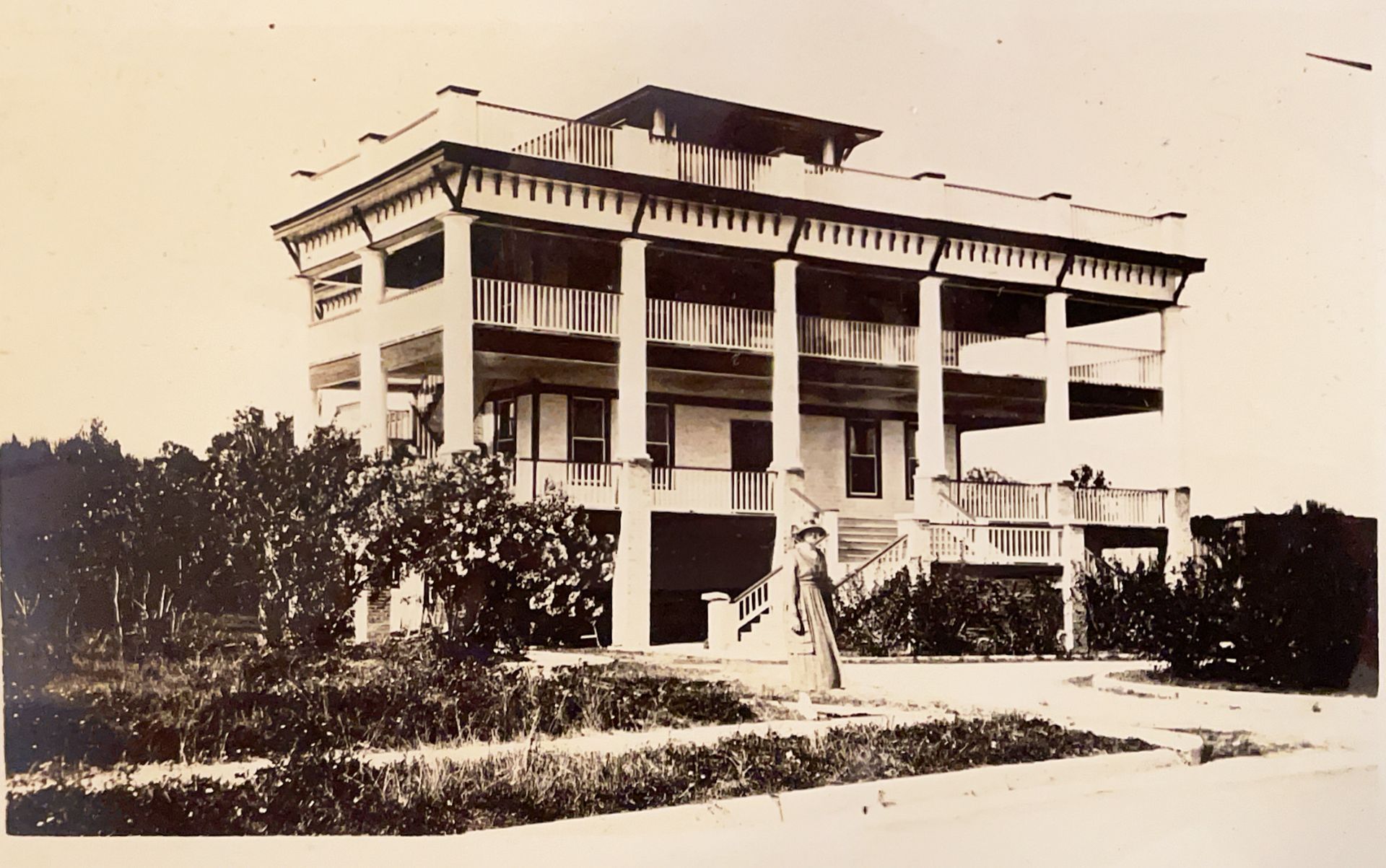 A black and white photo of a large house with columns