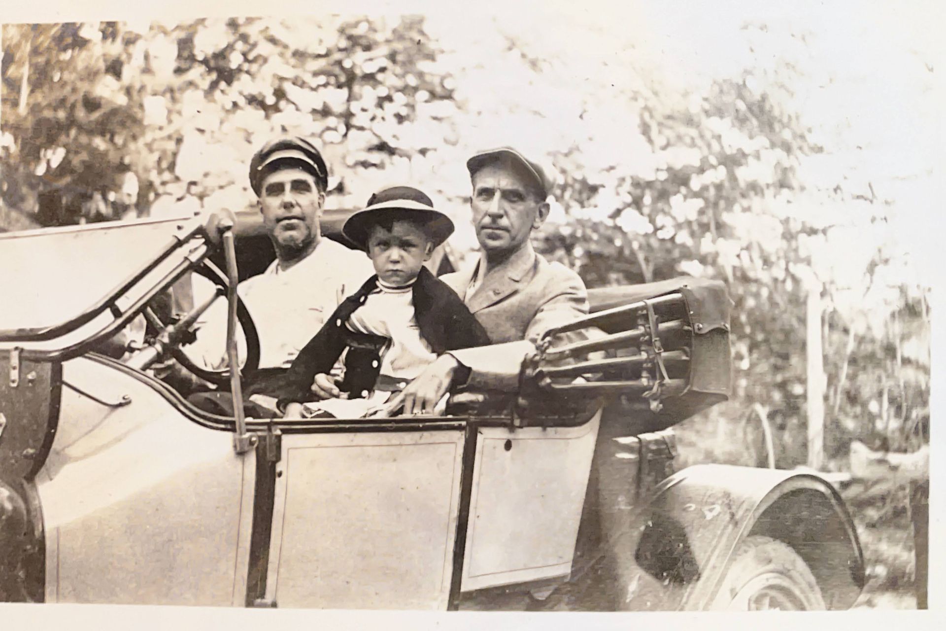 A black and white photo of three men and a child in a car