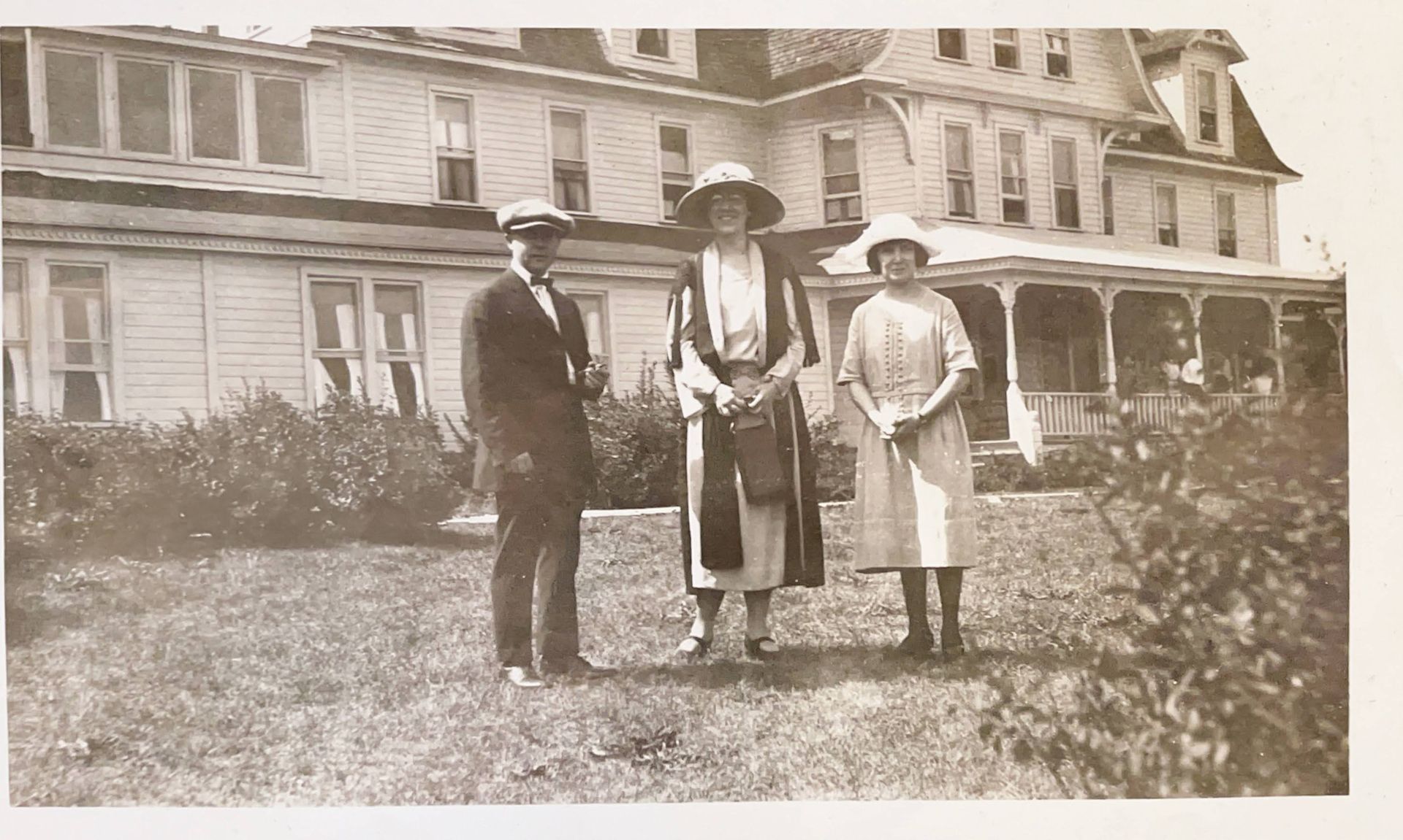 A black and white photo of three people standing in front of a house