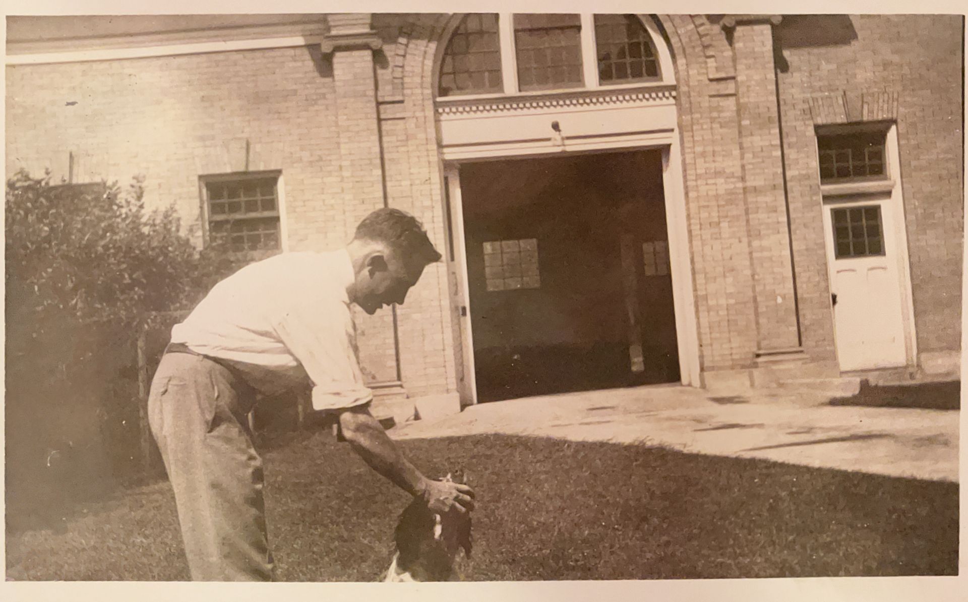 A black and white photo of a man standing in front of a building