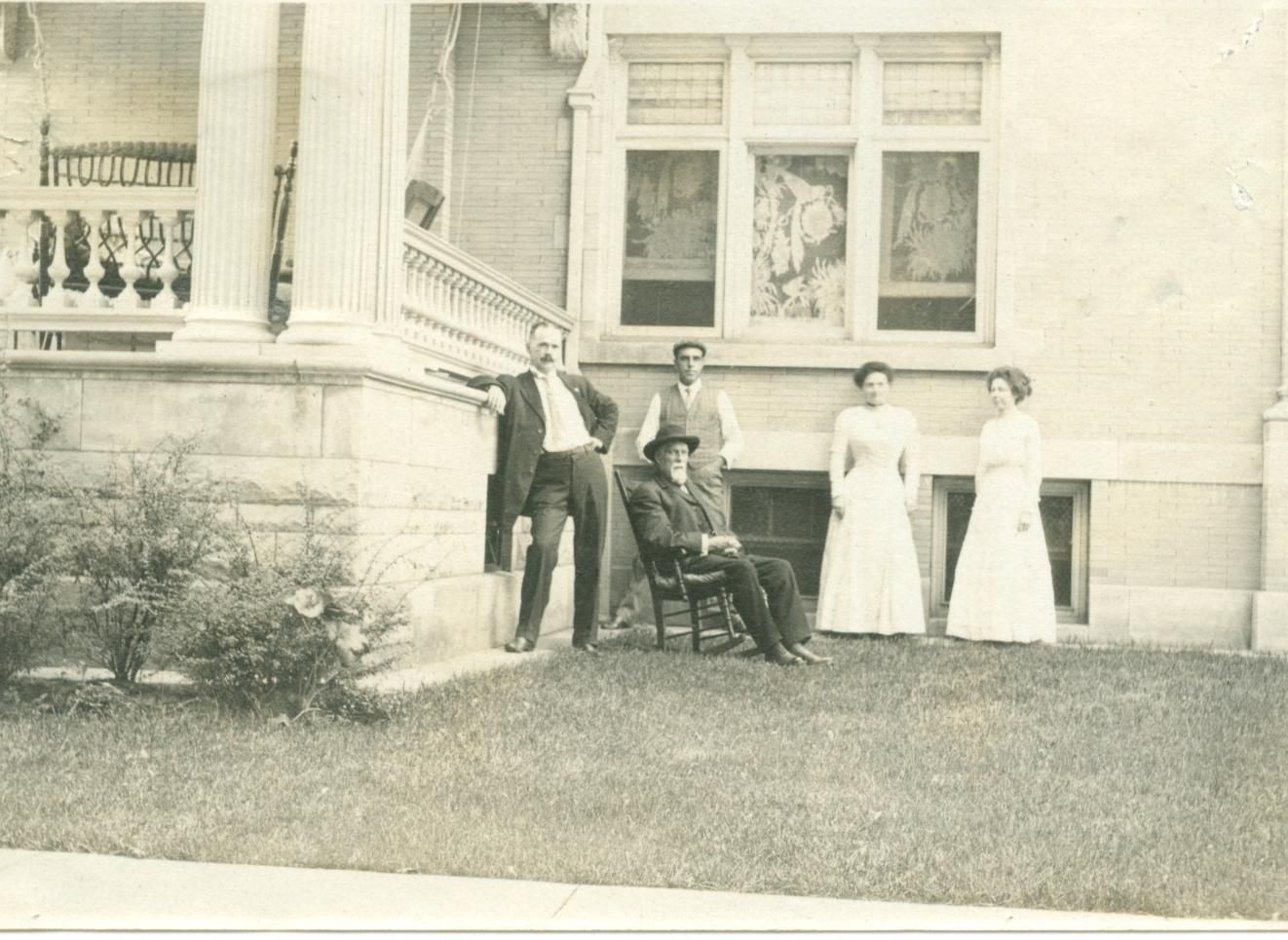 A group of people are posing for a picture in front of a house