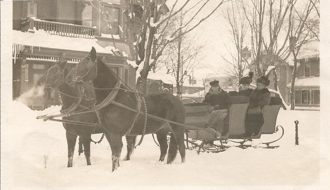 A black and white photo of a horse drawn carriage in the snow