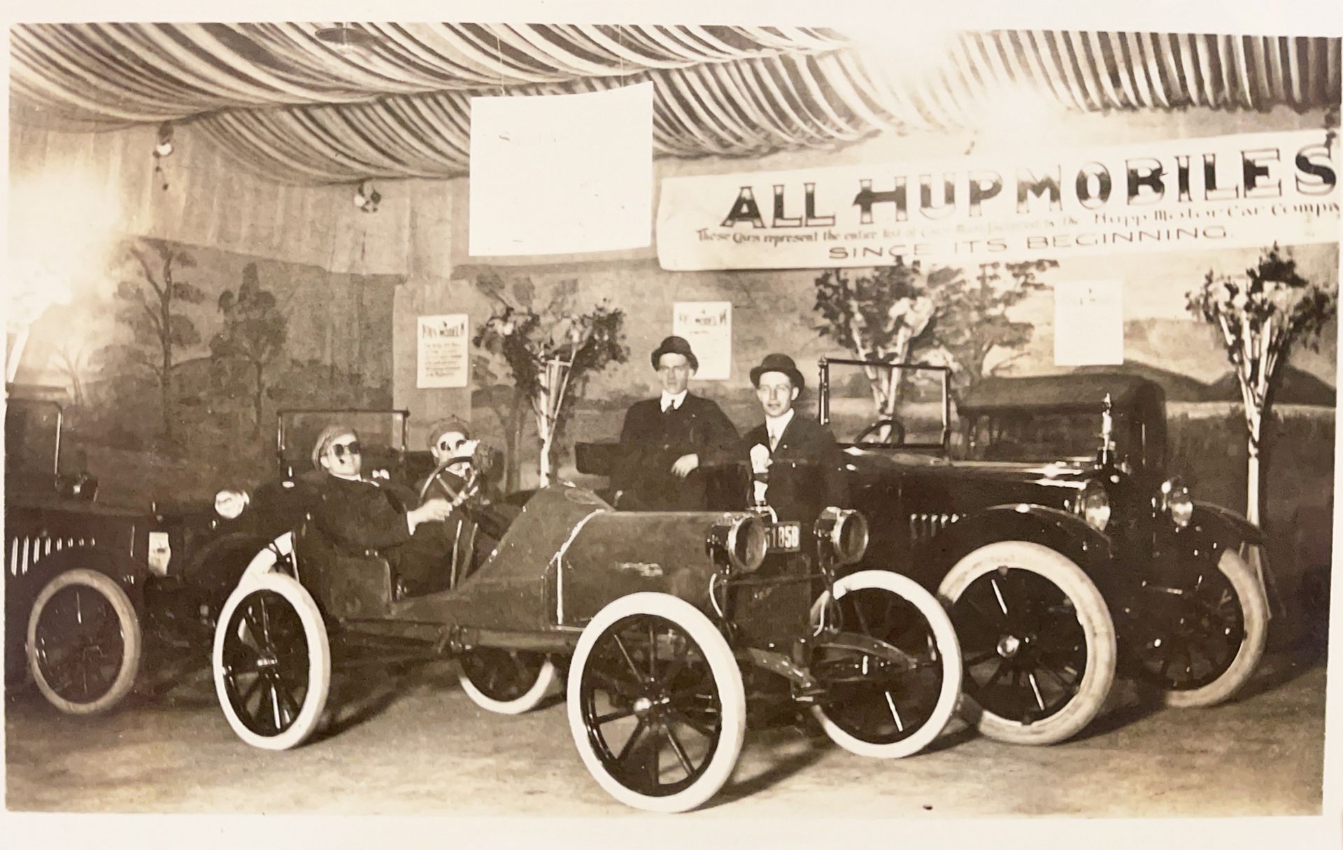 A group of old cars are in a room with a sign that says all hippomobiles