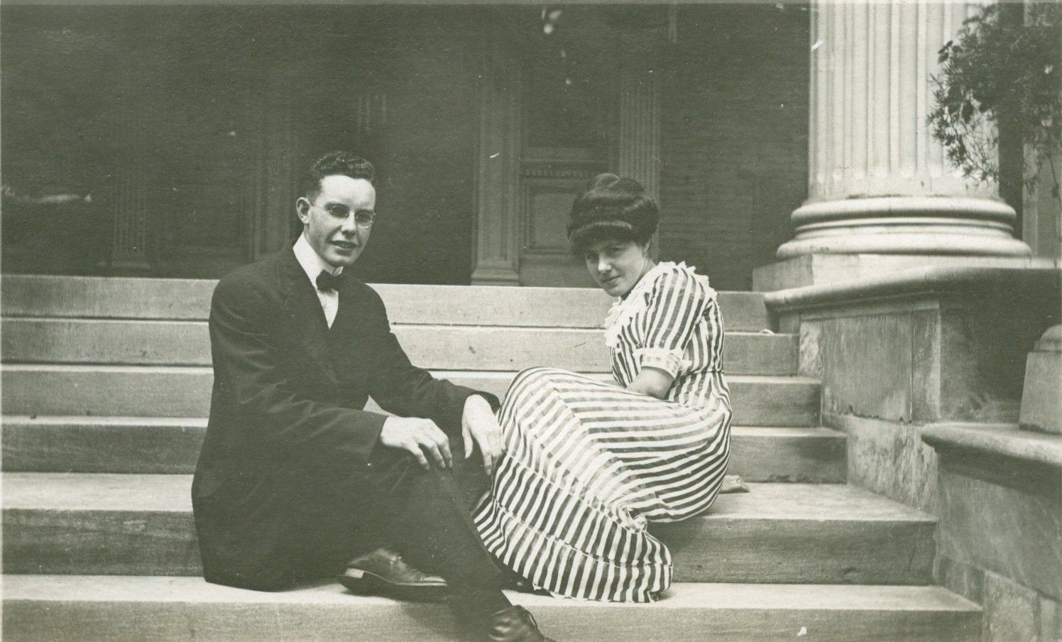 A man and a woman are sitting on the steps of a building