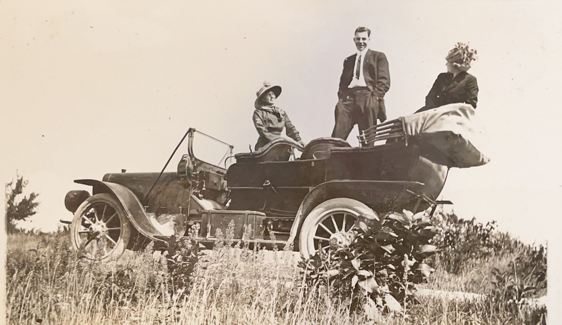 A black and white photo of three people in an old car
