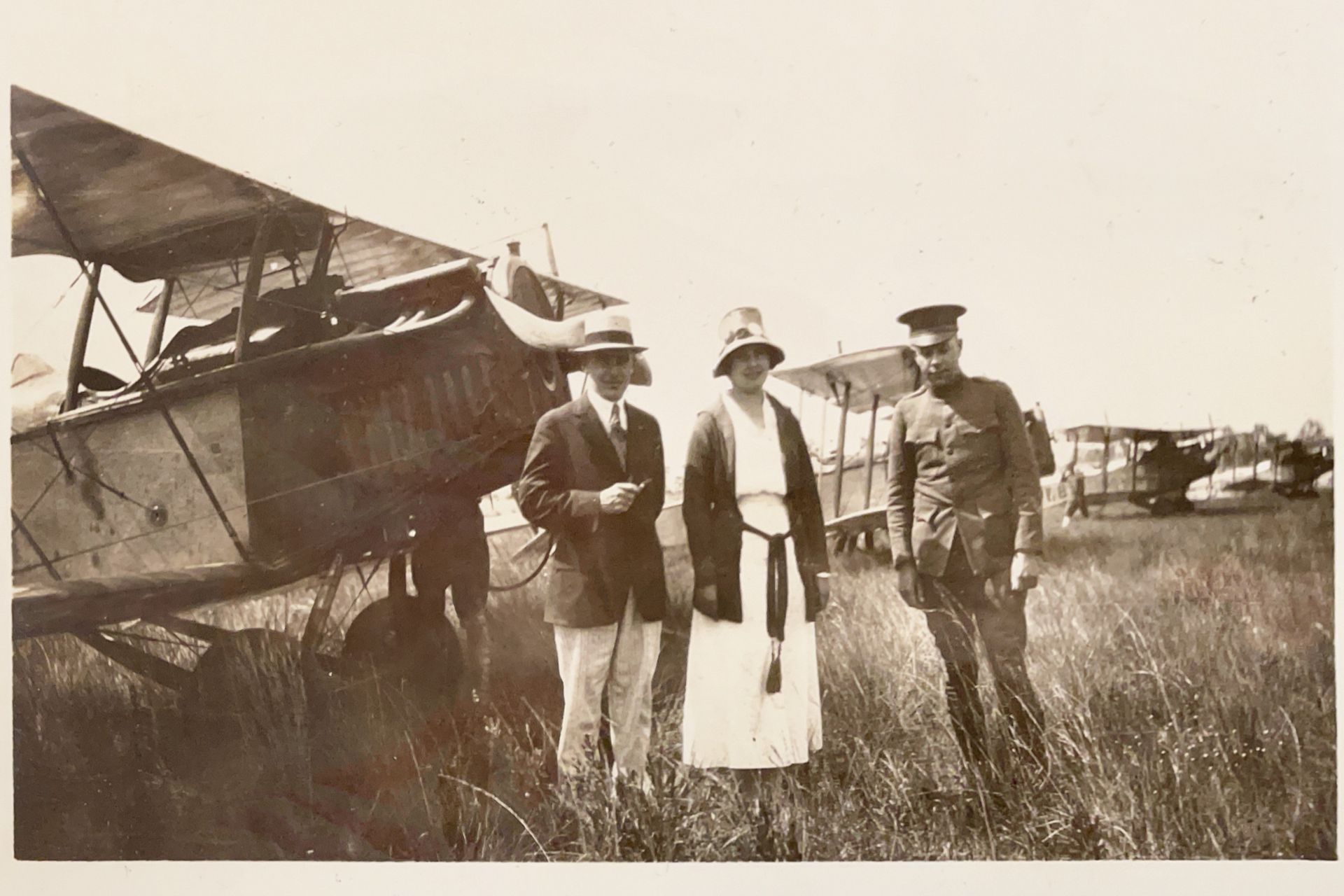 A black and white photo of three people standing in front of an airplane