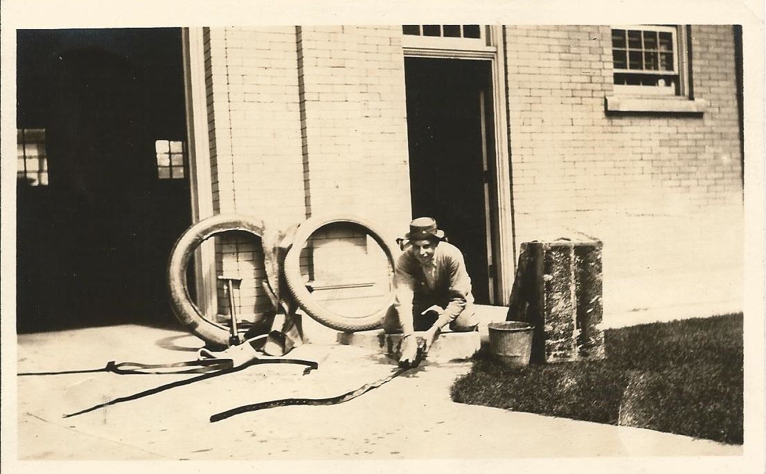A black and white photo of a man in front of a brick building